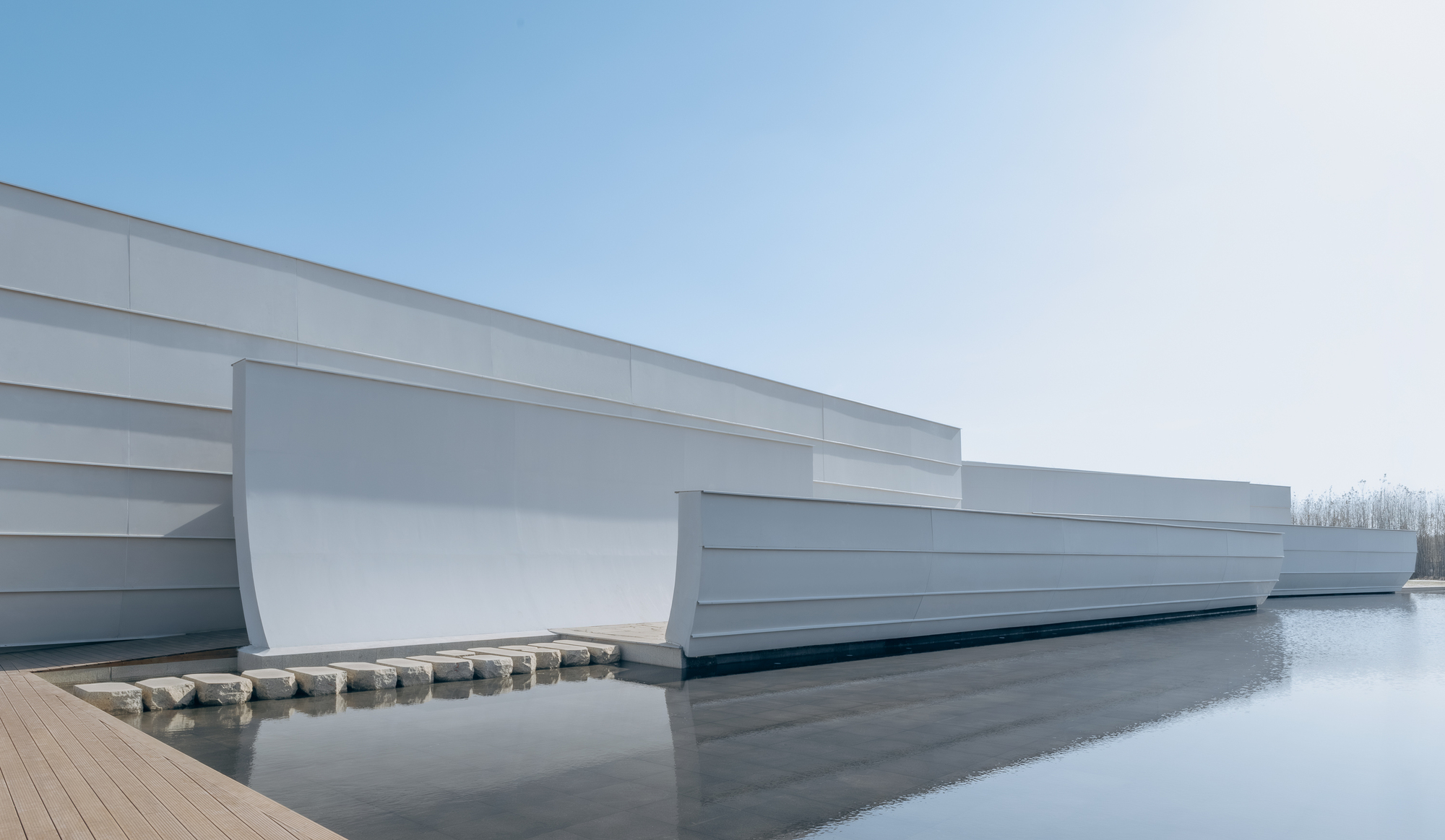 Long view of the layered white facade extending over still water under overcast skies