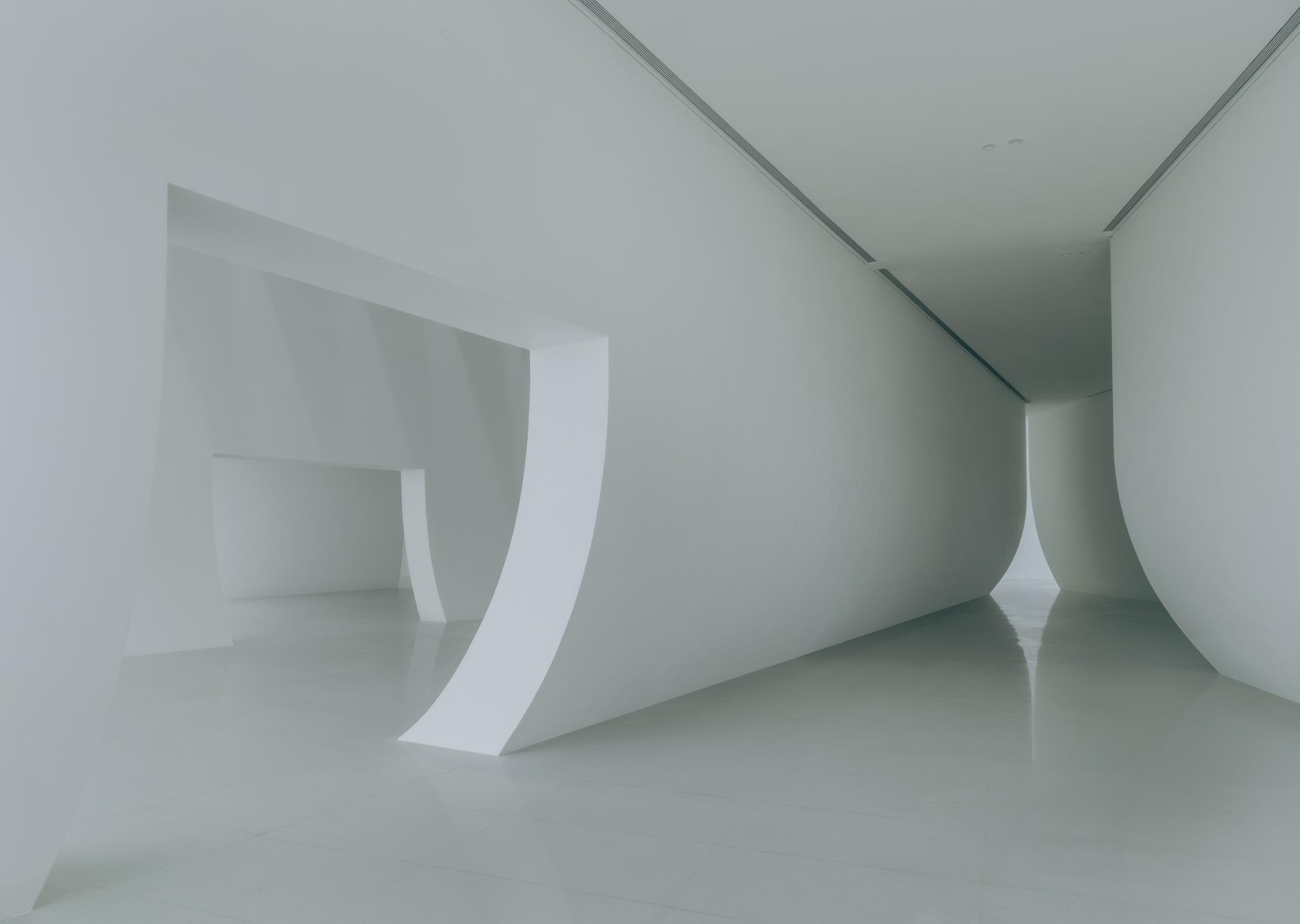 Close-up of the curved white wall meeting the polished floor in the gallery space