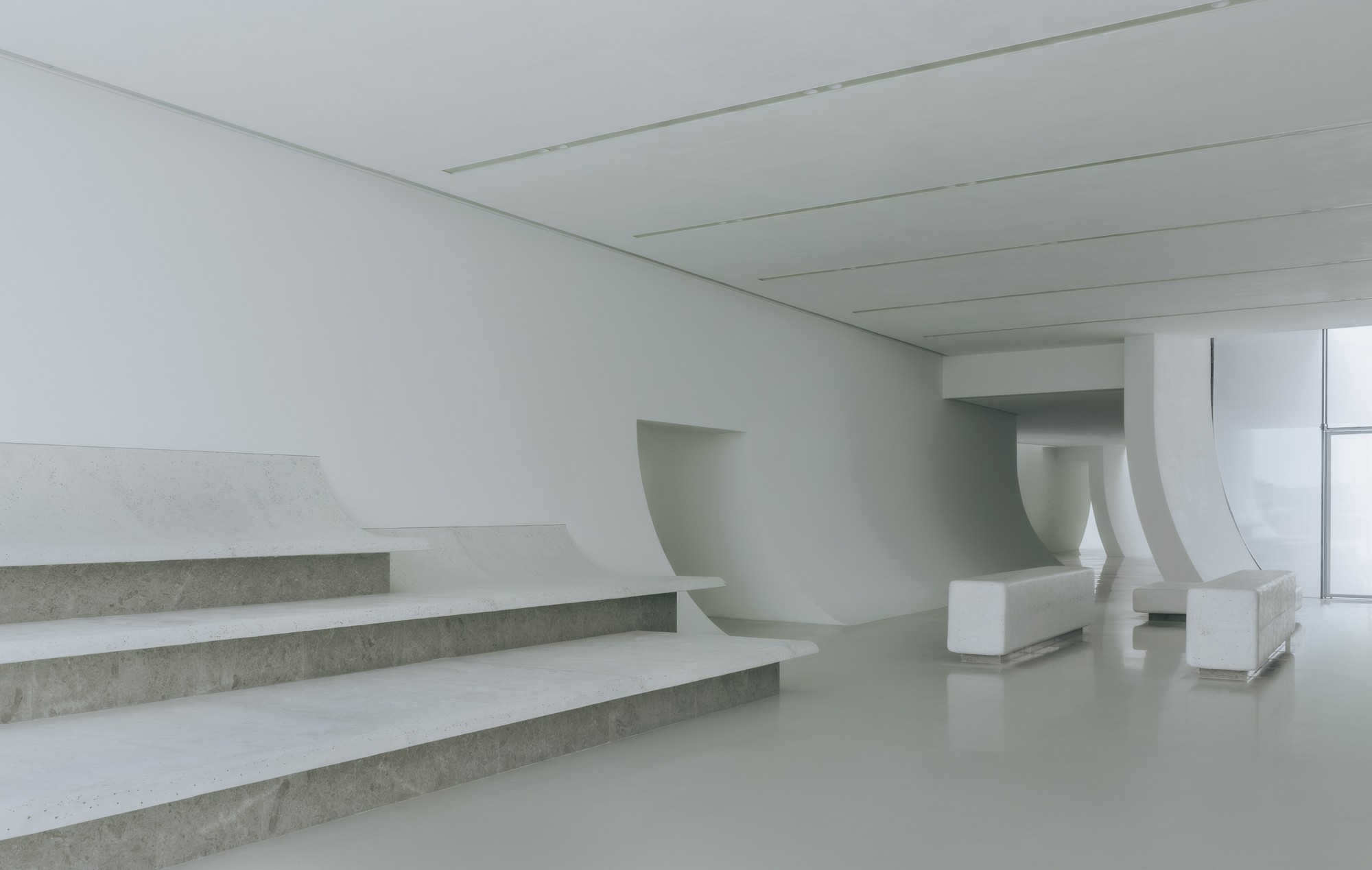 Interior view of the broad staircase with exposed concrete treads and curved white balustrades