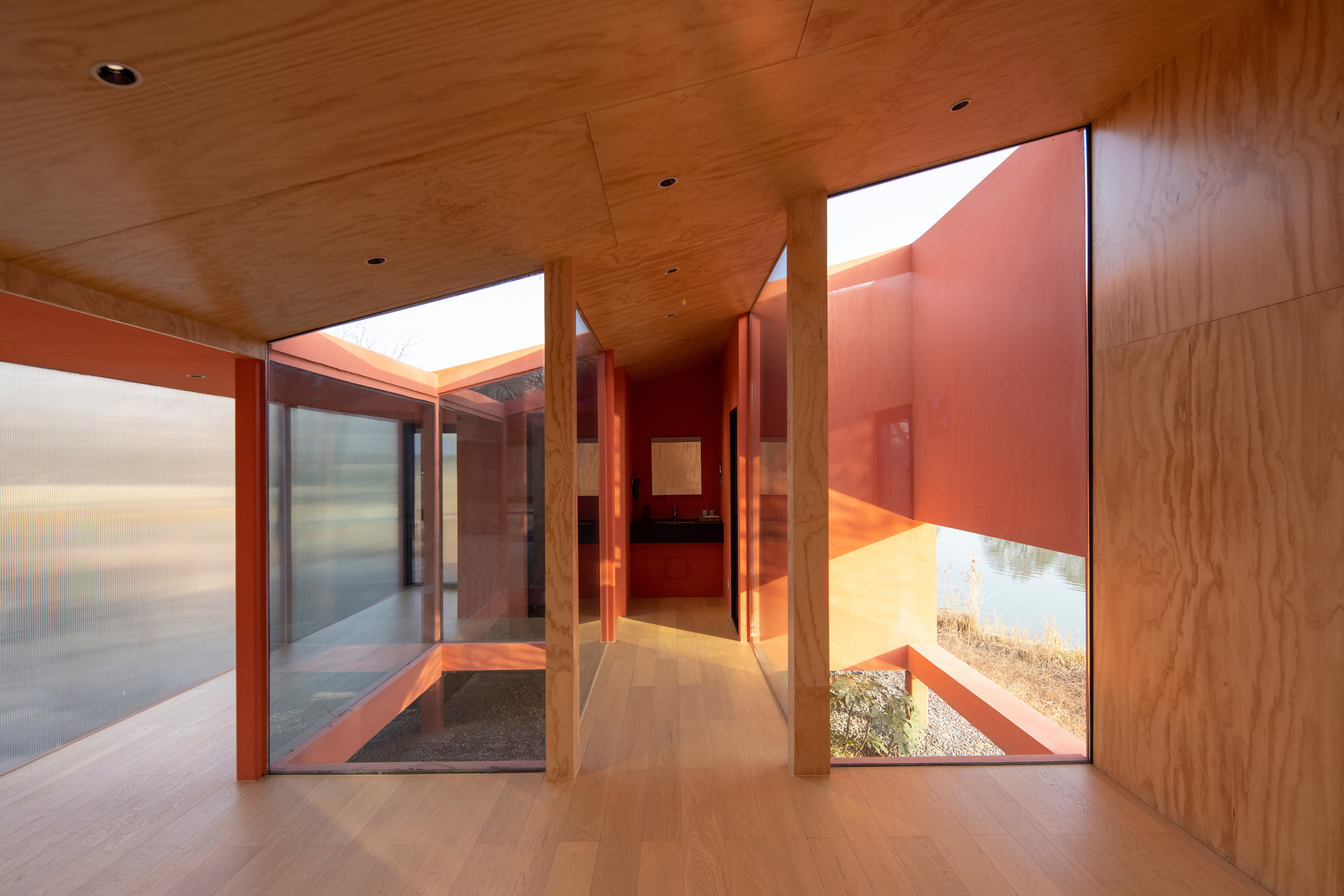Hallway with wooden ceiling and floor connecting glazed courtyards beneath clerestory openings