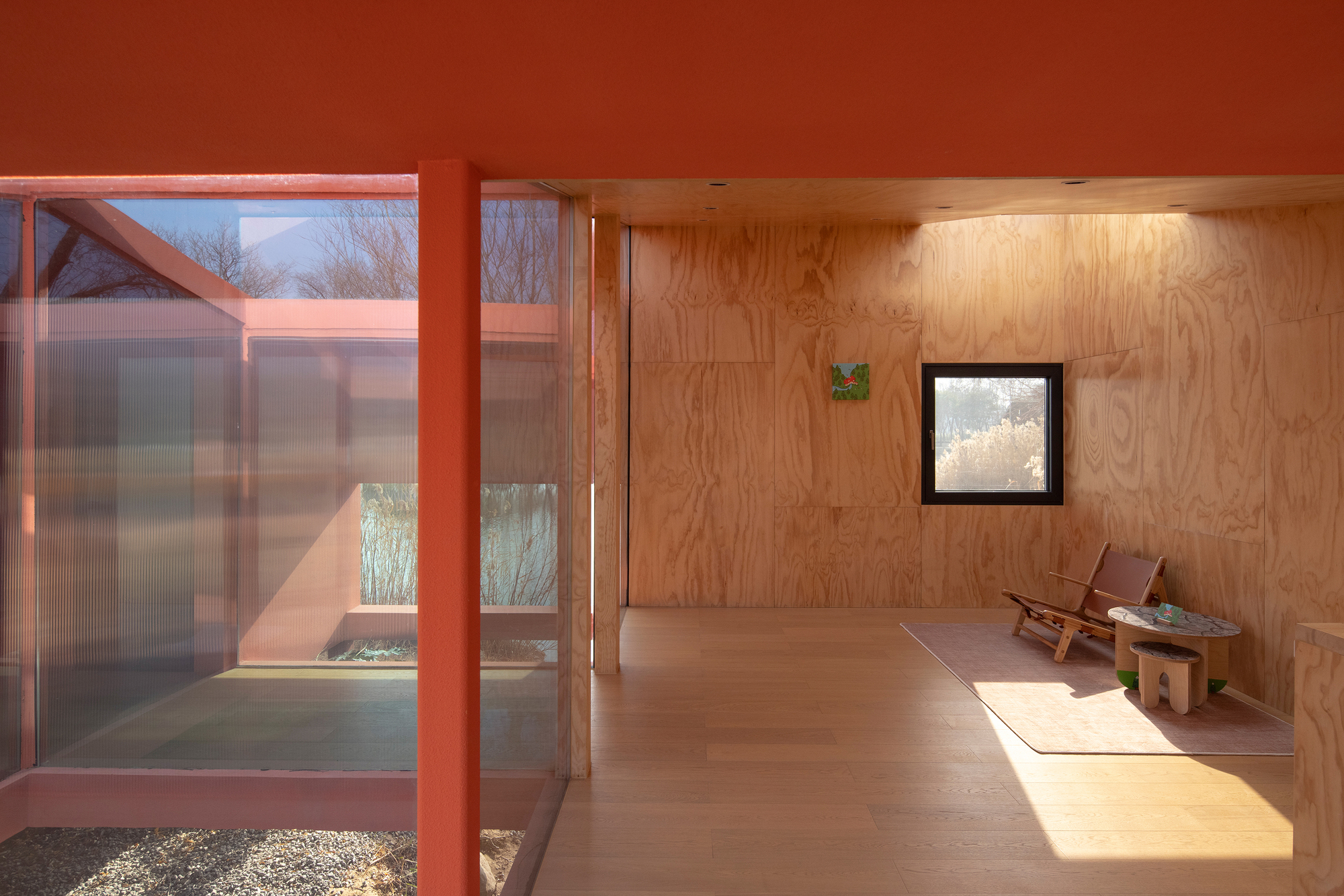 Plywood lined interior with sunlight streaming through translucent glazing onto a concrete floor