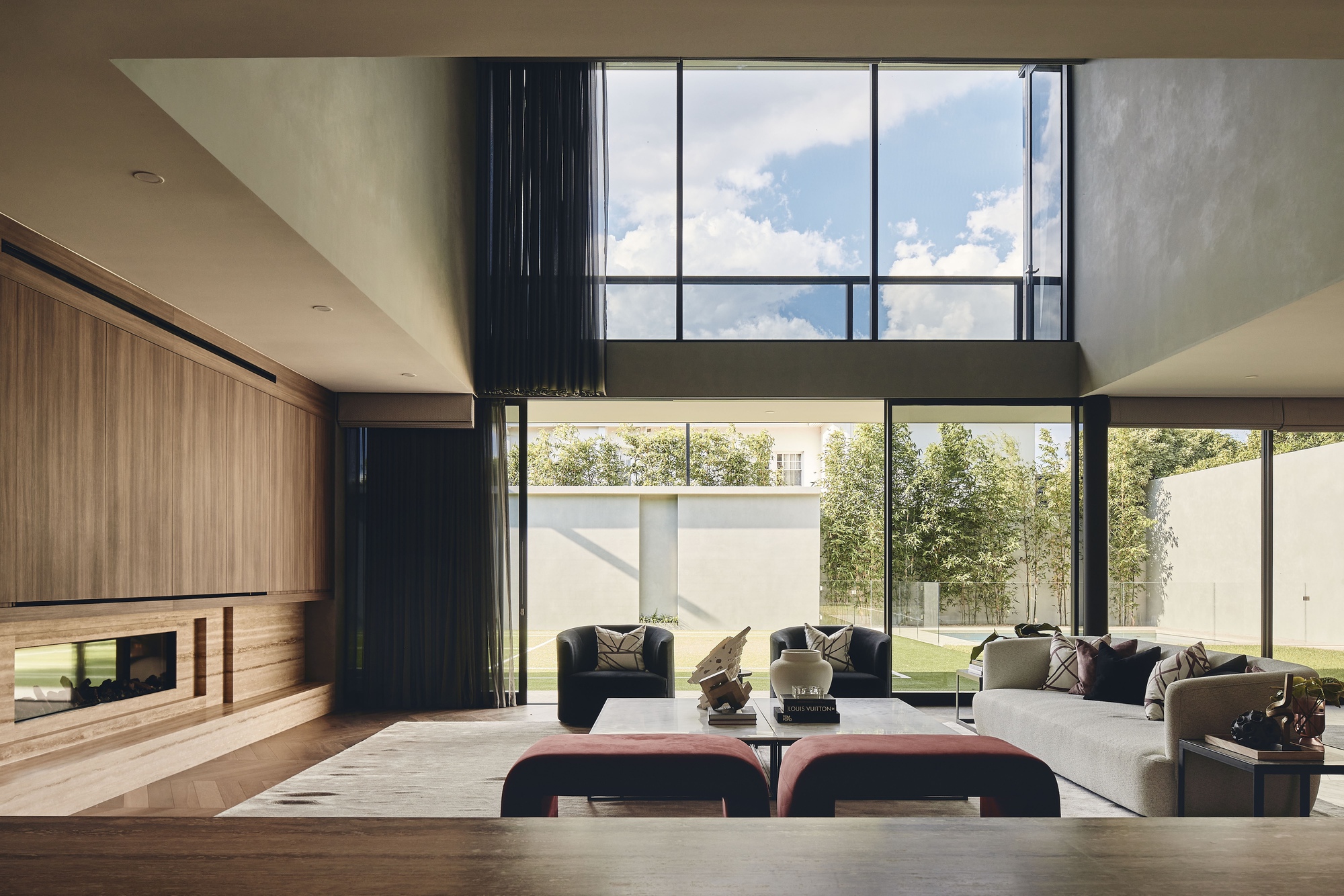 Double-height living space with floor-to-ceiling glazing overlooking the lawn and clerestory windows above