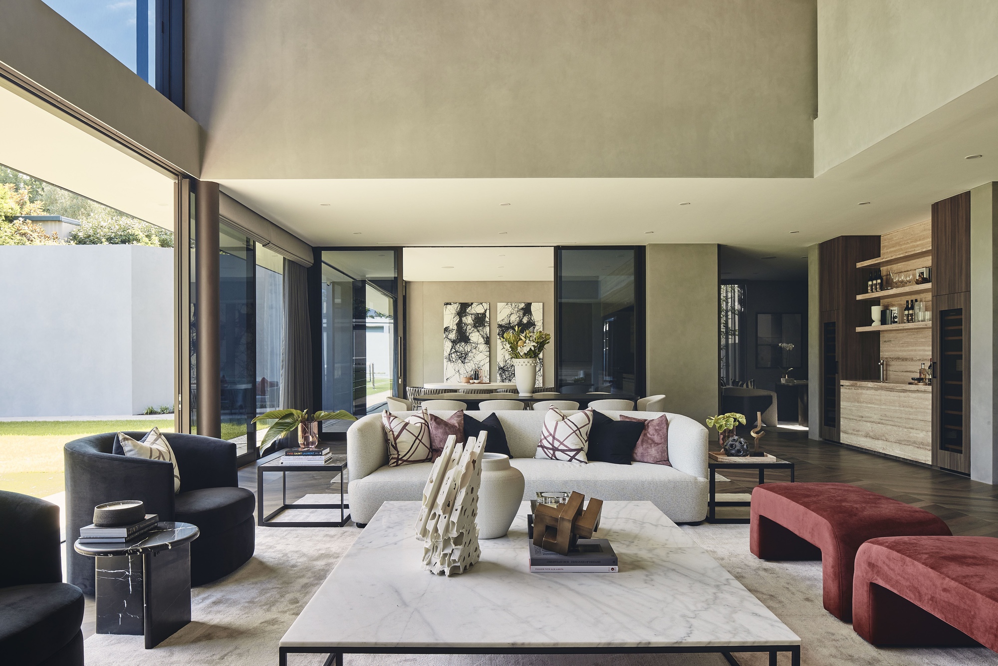 Open-plan living space with concrete ceiling planes and floor-to-ceiling glazing overlooking a courtyard