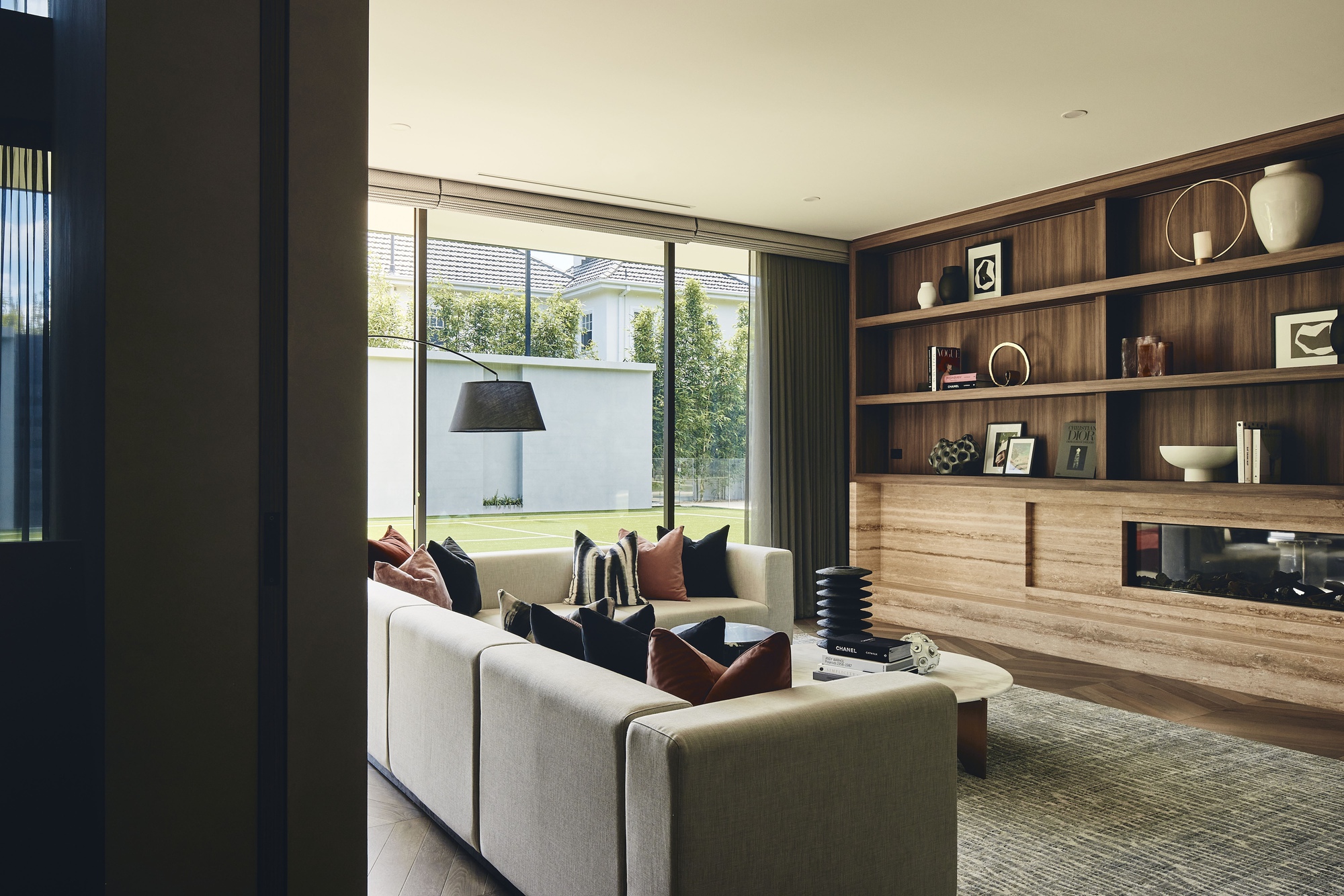 Living area with timber shelving wall and sliding glass doors opening to a lawn