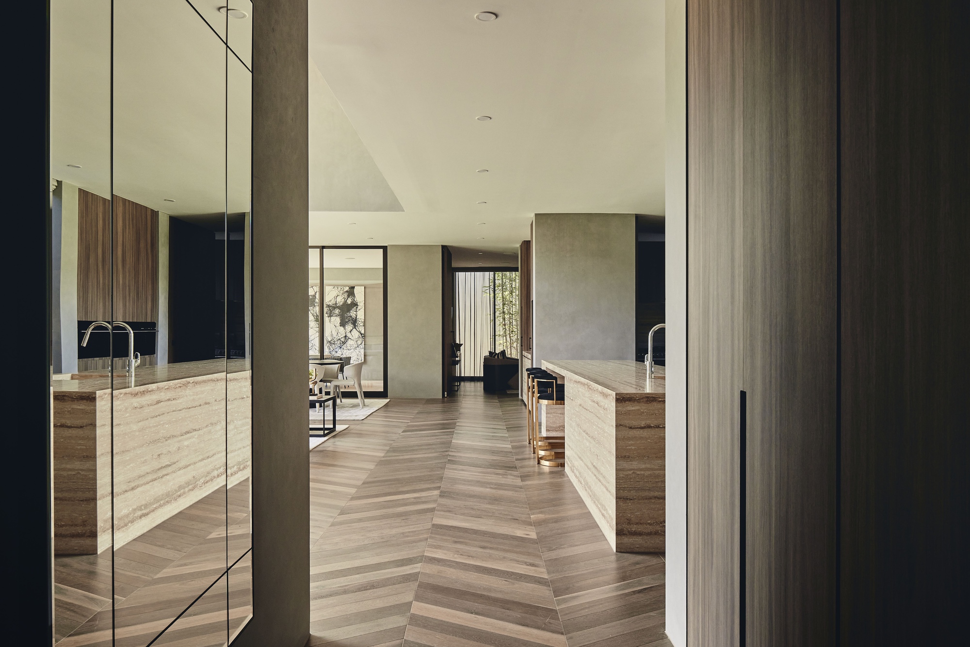 View through doorway into kitchen with chevron timber flooring and concrete wall panels