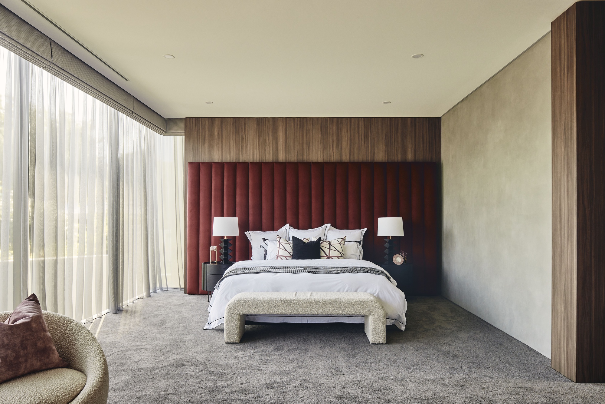 Bedroom with maroon channel-tufted headboard and floor-to-ceiling curtains