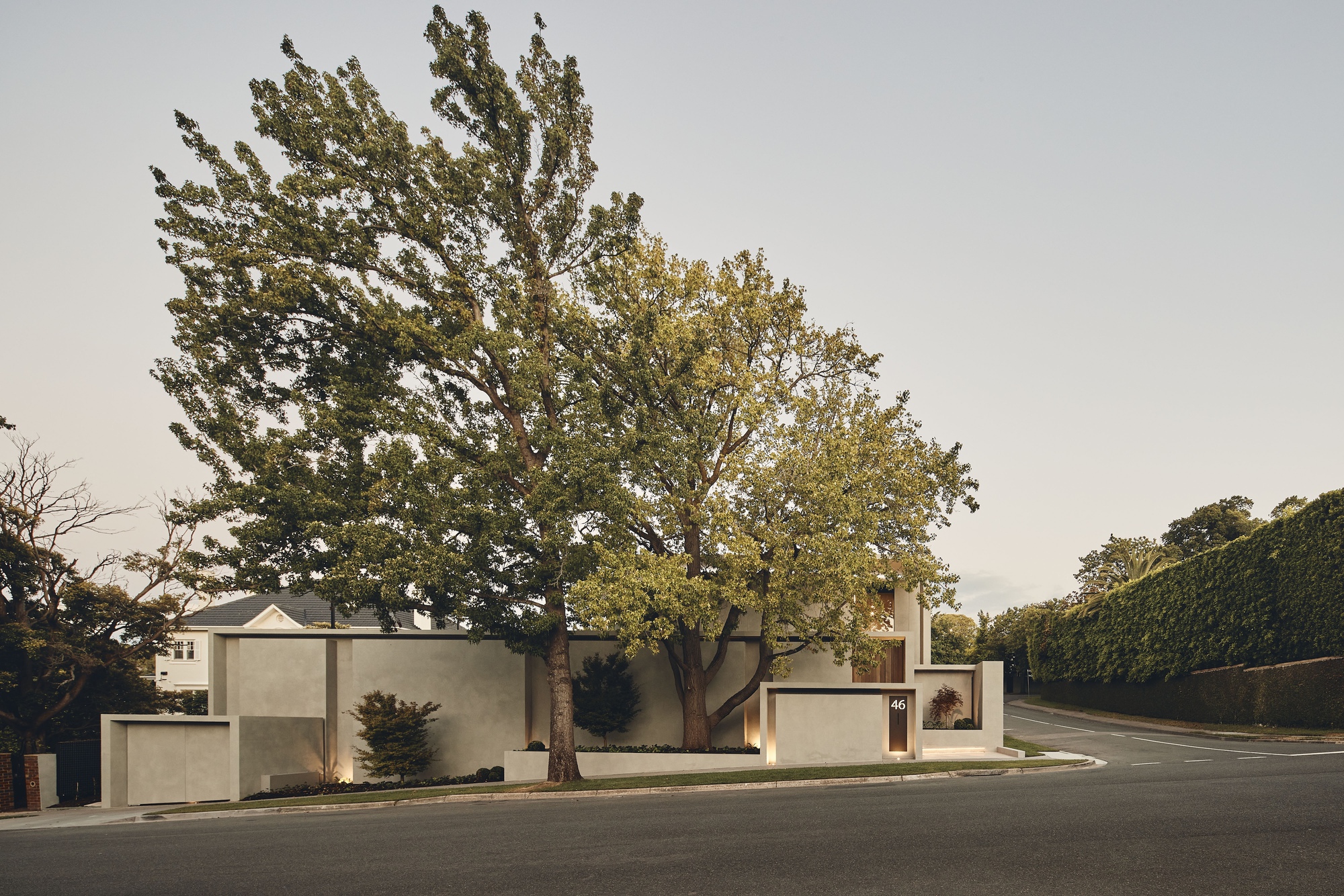 Street view showing the stacked concrete volumes framed by mature trees under an overcast sky