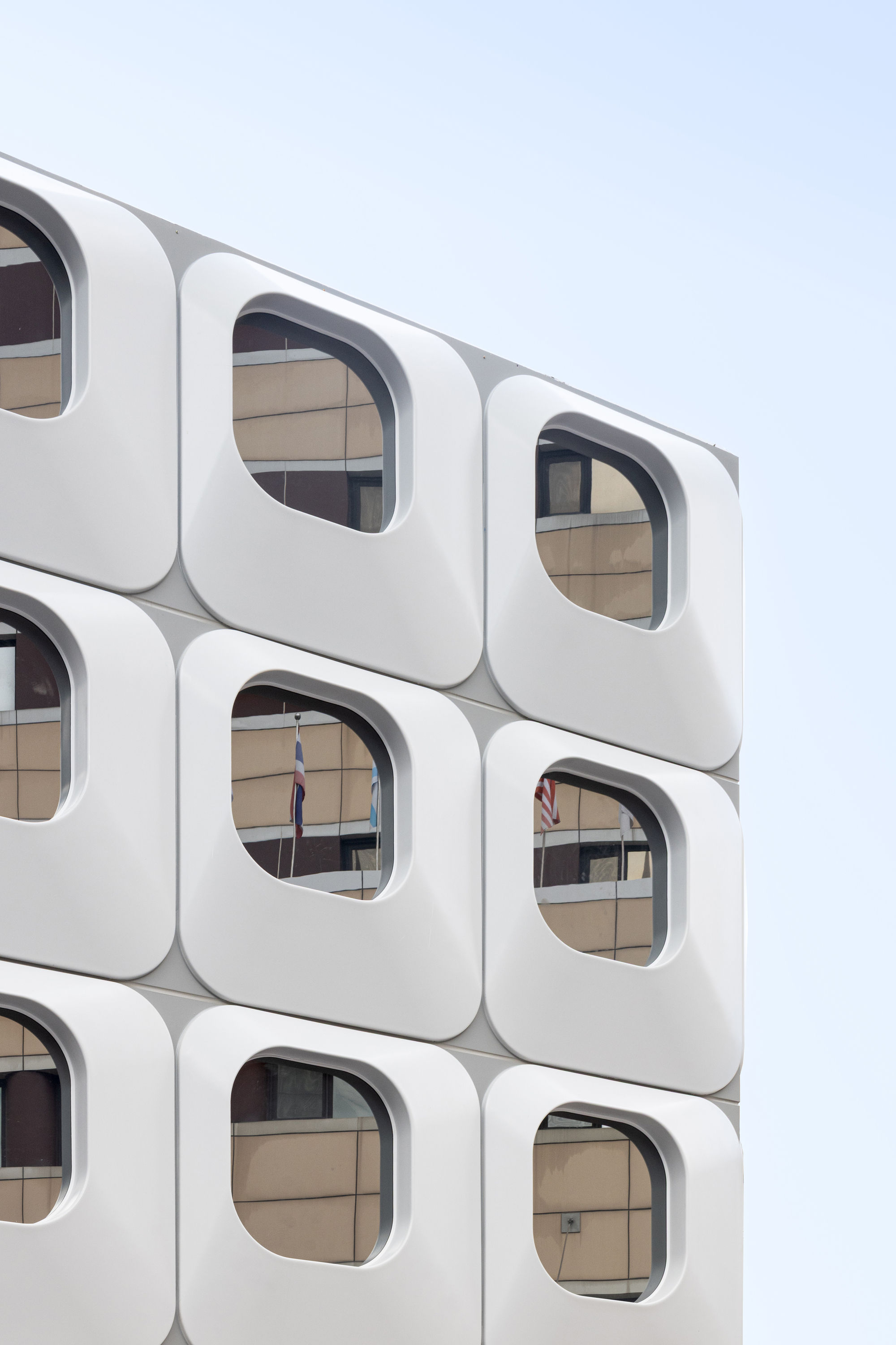 Close-up of white rounded-square window modules revealing interior office spaces through the glazing