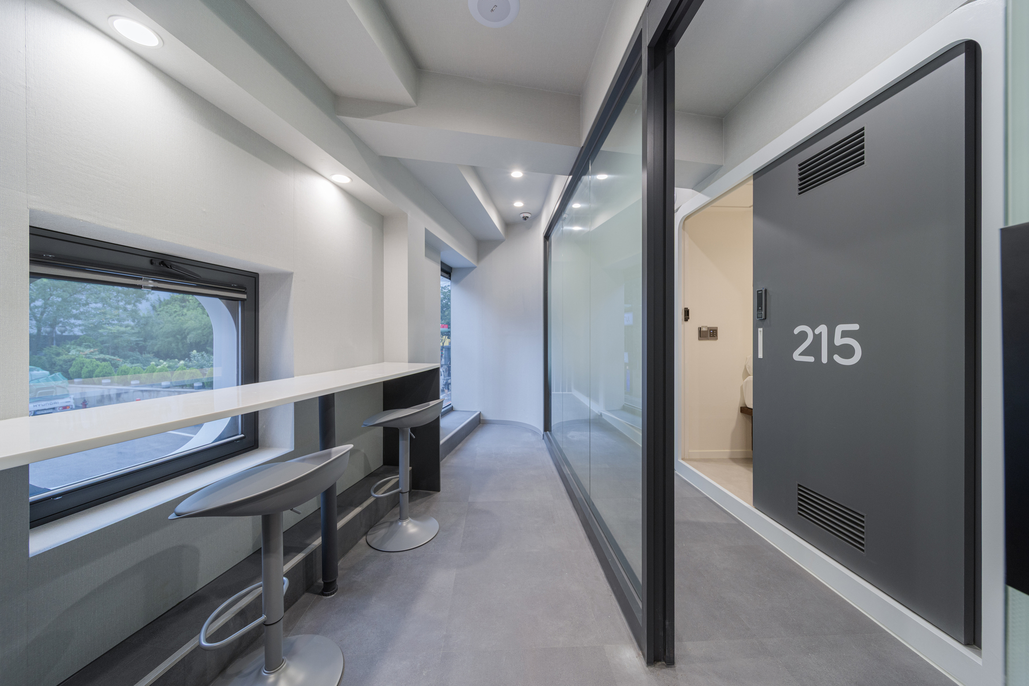 Corridor with built-in seating alcove, numbered door and glass partition at dusk