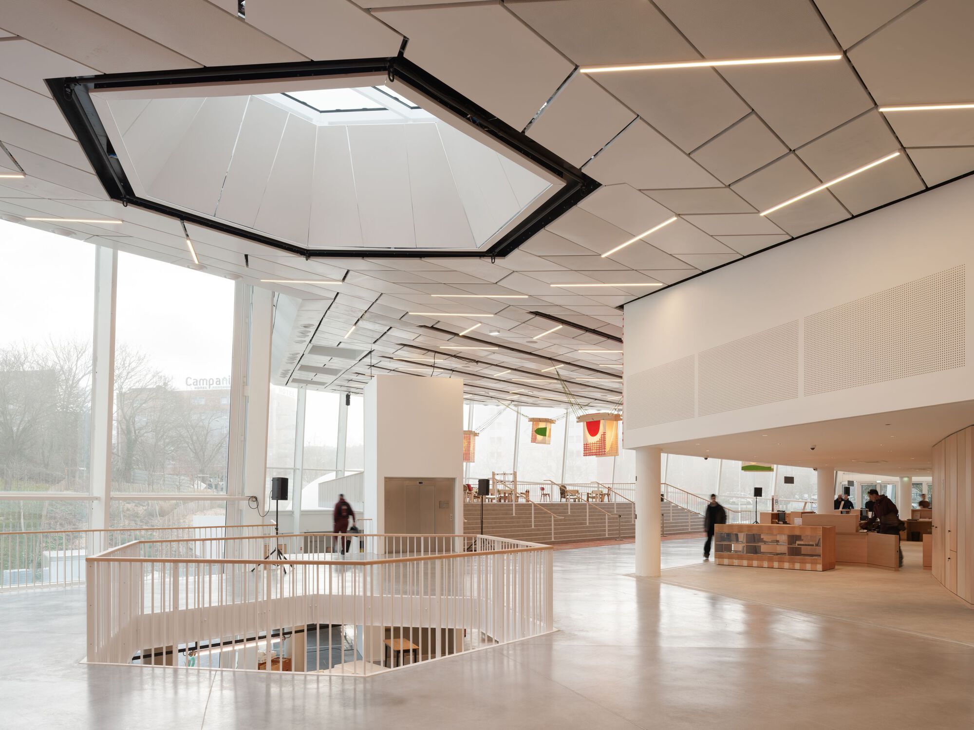 Interior gallery space with geometric ceiling panels, hexagonal skylight and curved stairwell opening