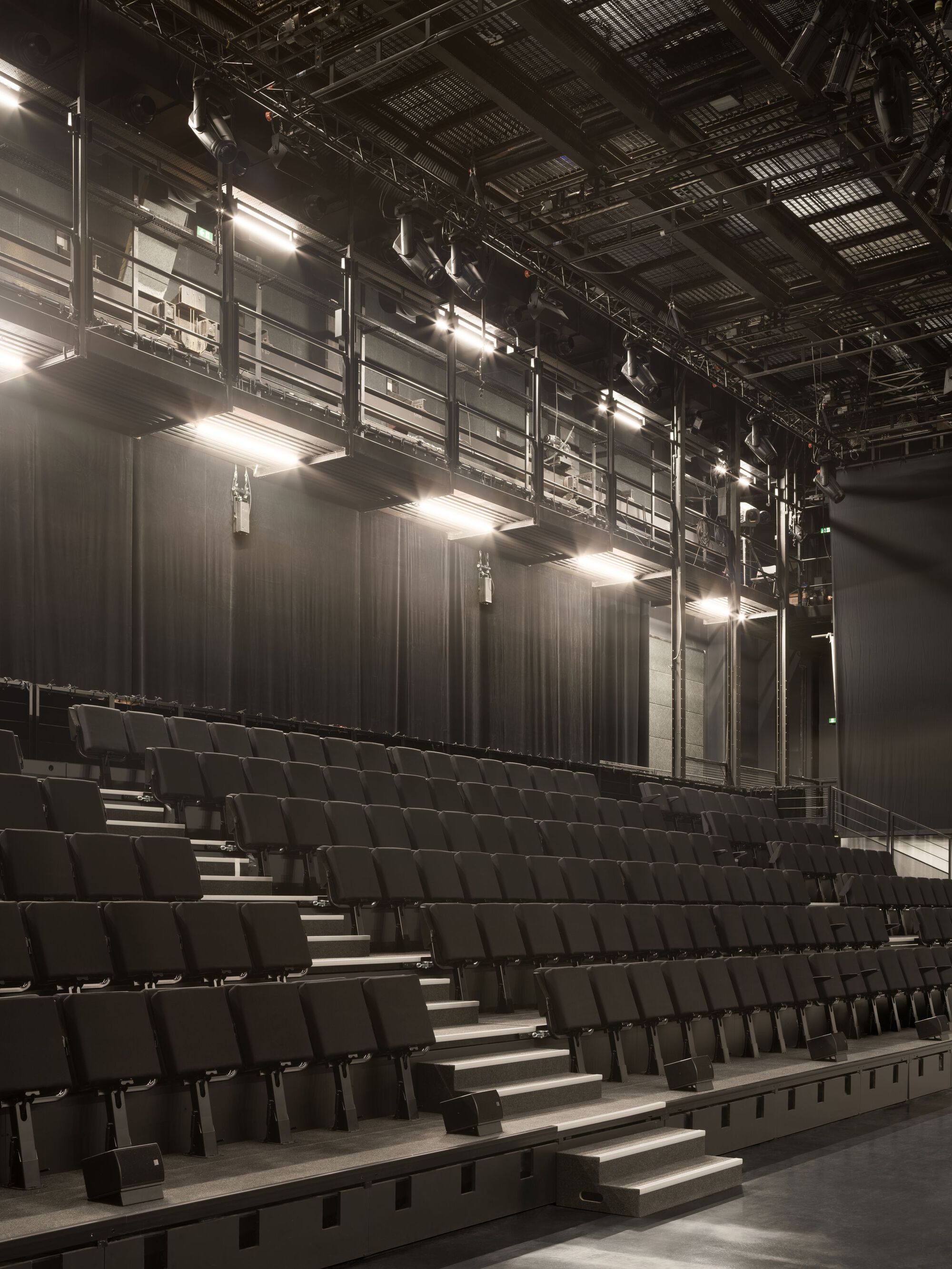 Angled view of the raked seating rows with stage curtains and suspended lighting infrastructure