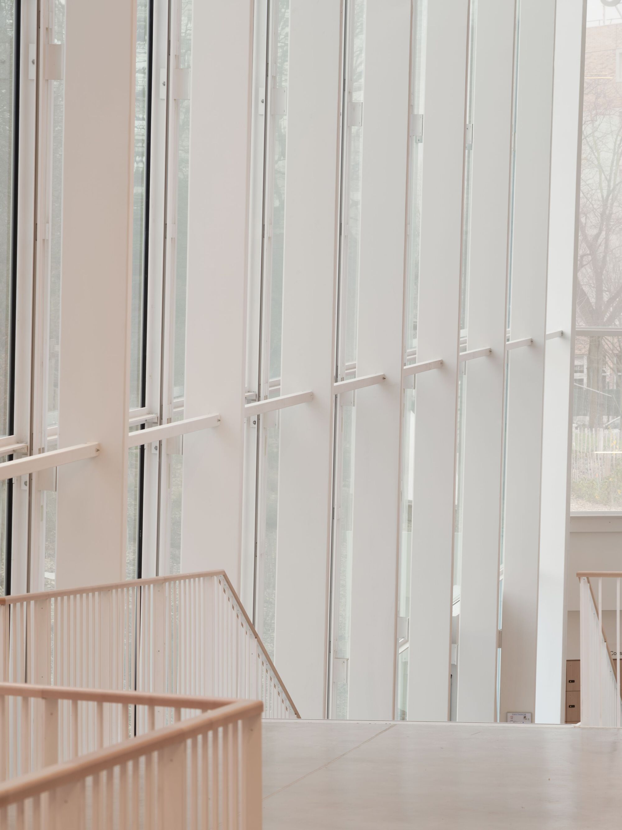 Interior vertical screen wall with slender white fins beside a timber-railed staircase