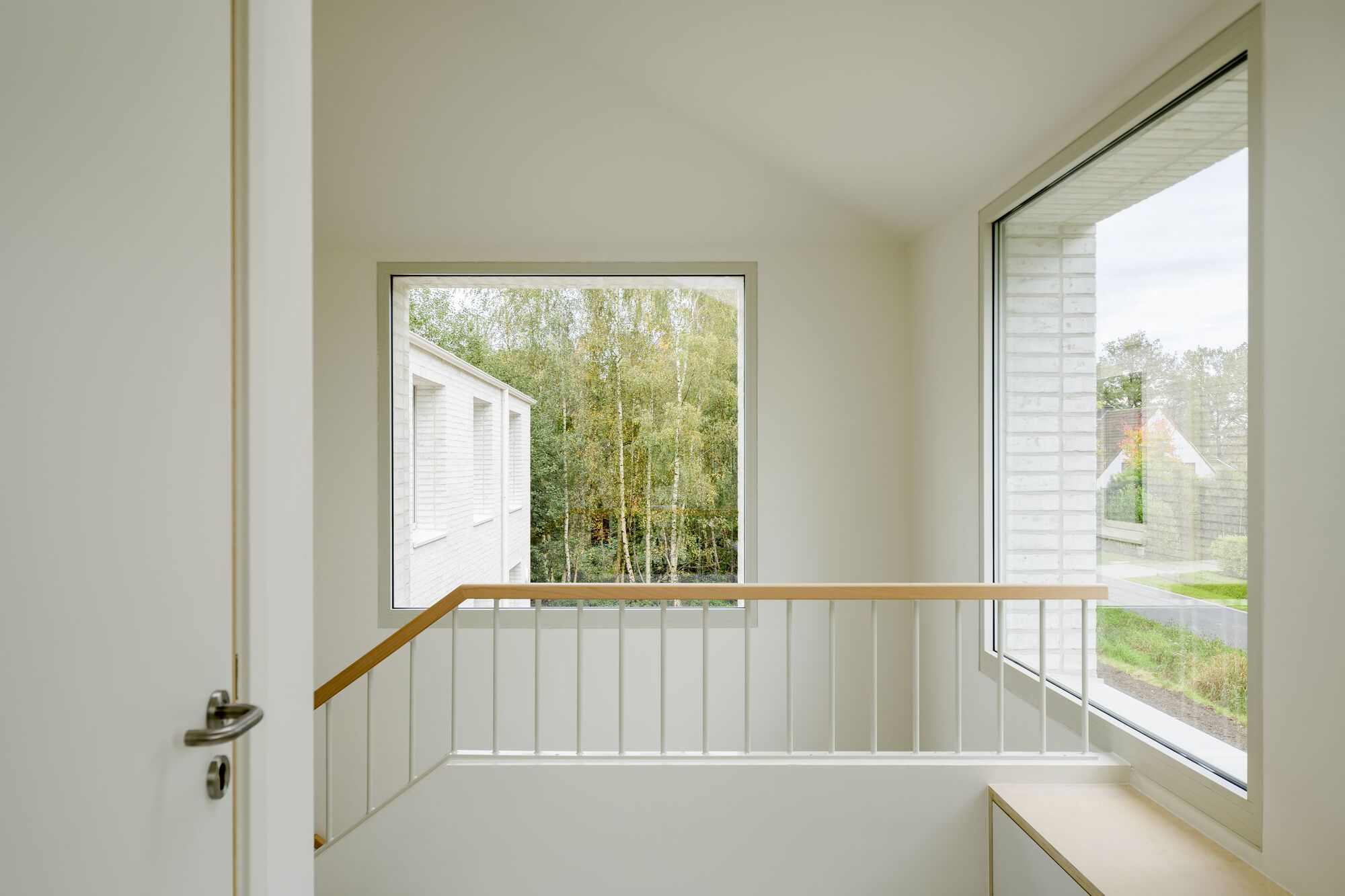 Upper landing with timber handrail and corner windows framing neighboring gabled roofline