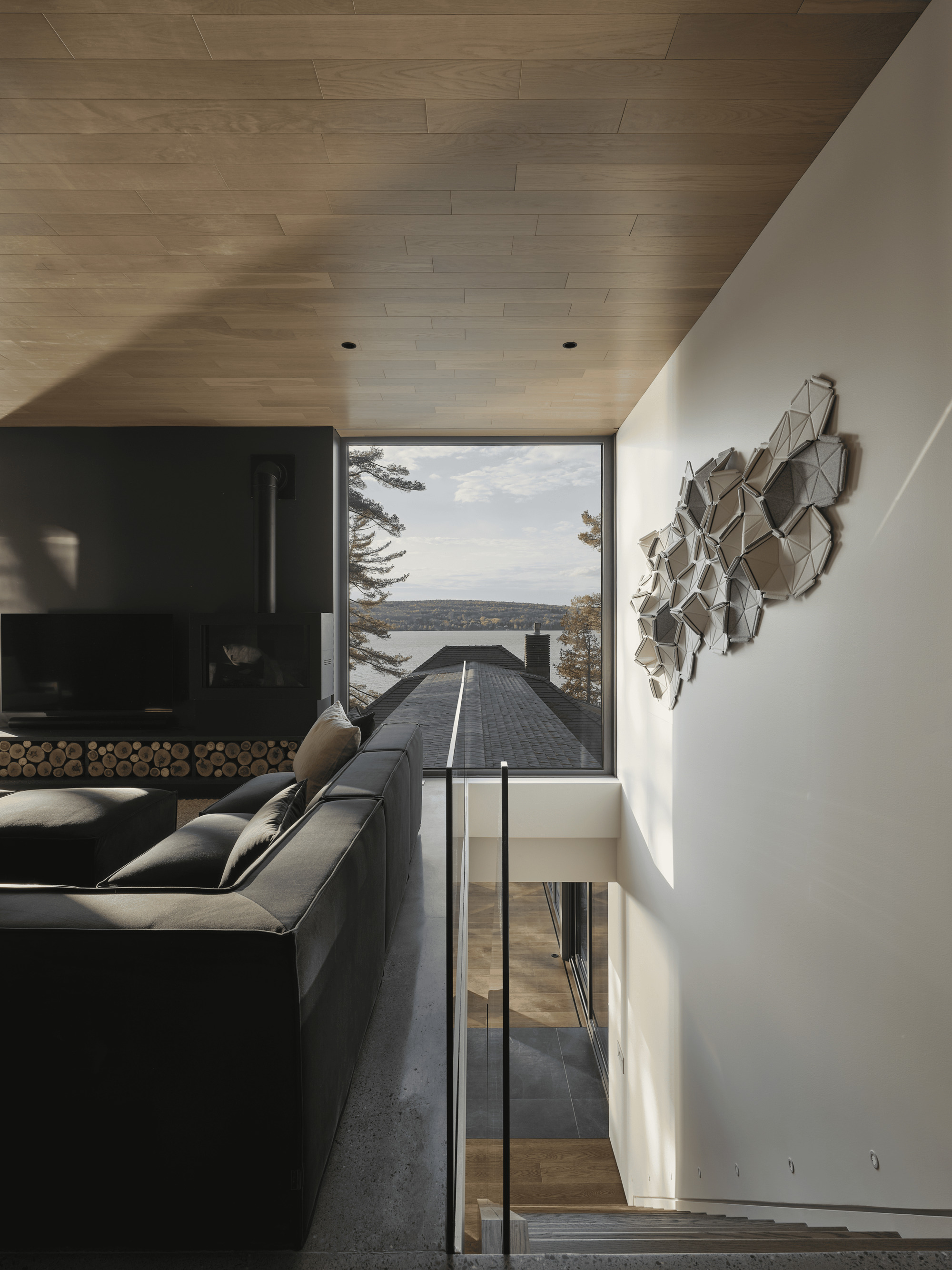 Living area with wood plank ceiling and picture window framing a walkway extending toward the lake