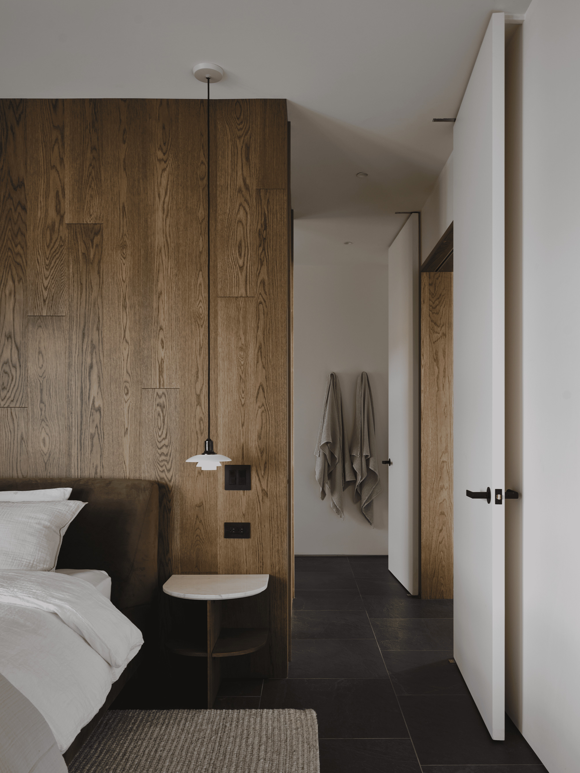 Bedroom with floor-to-ceiling oak paneling and pendant light beside the bed
