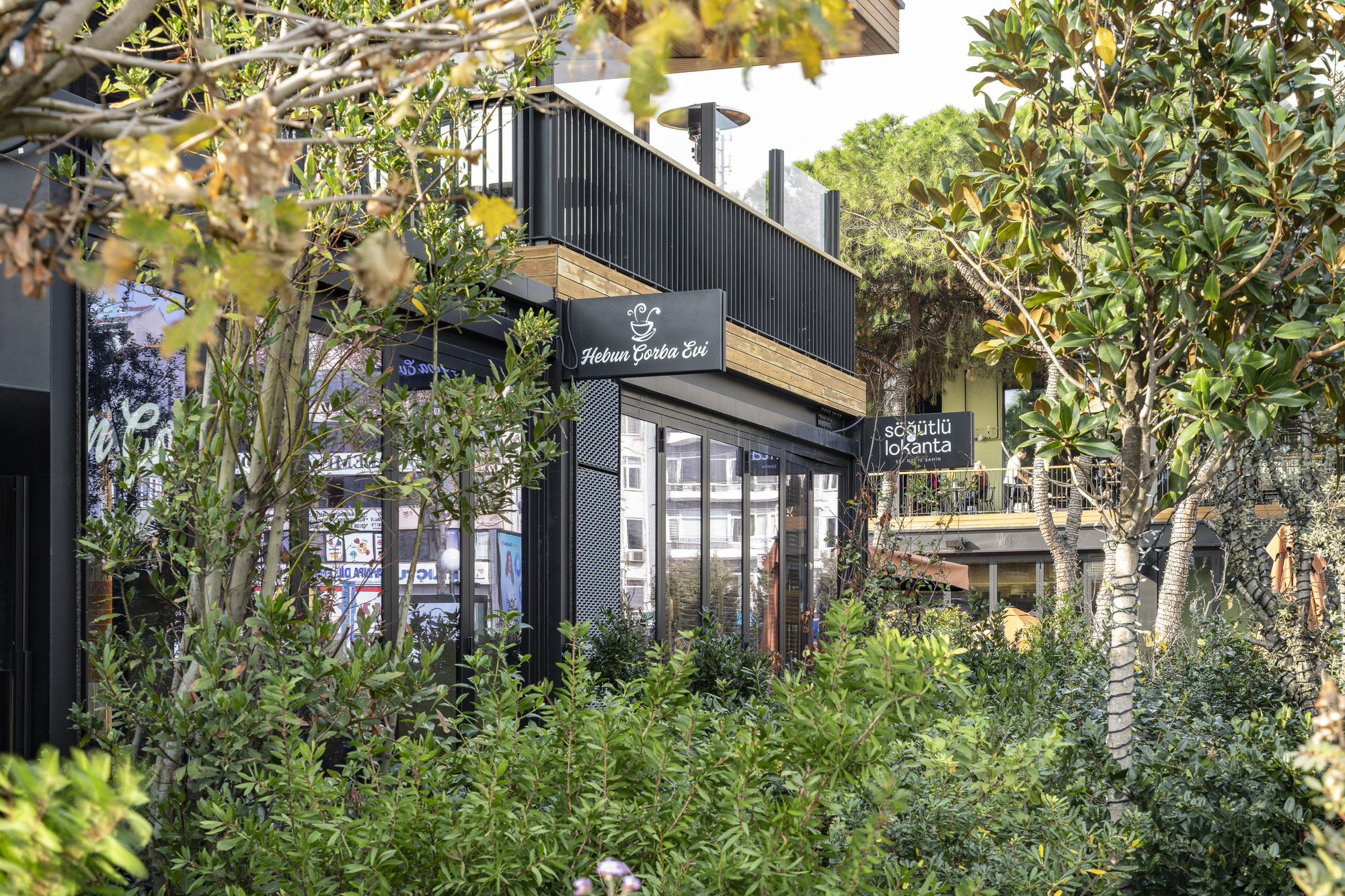 Black metal and timber retail kiosk framed by dense plantings and trees in foreground