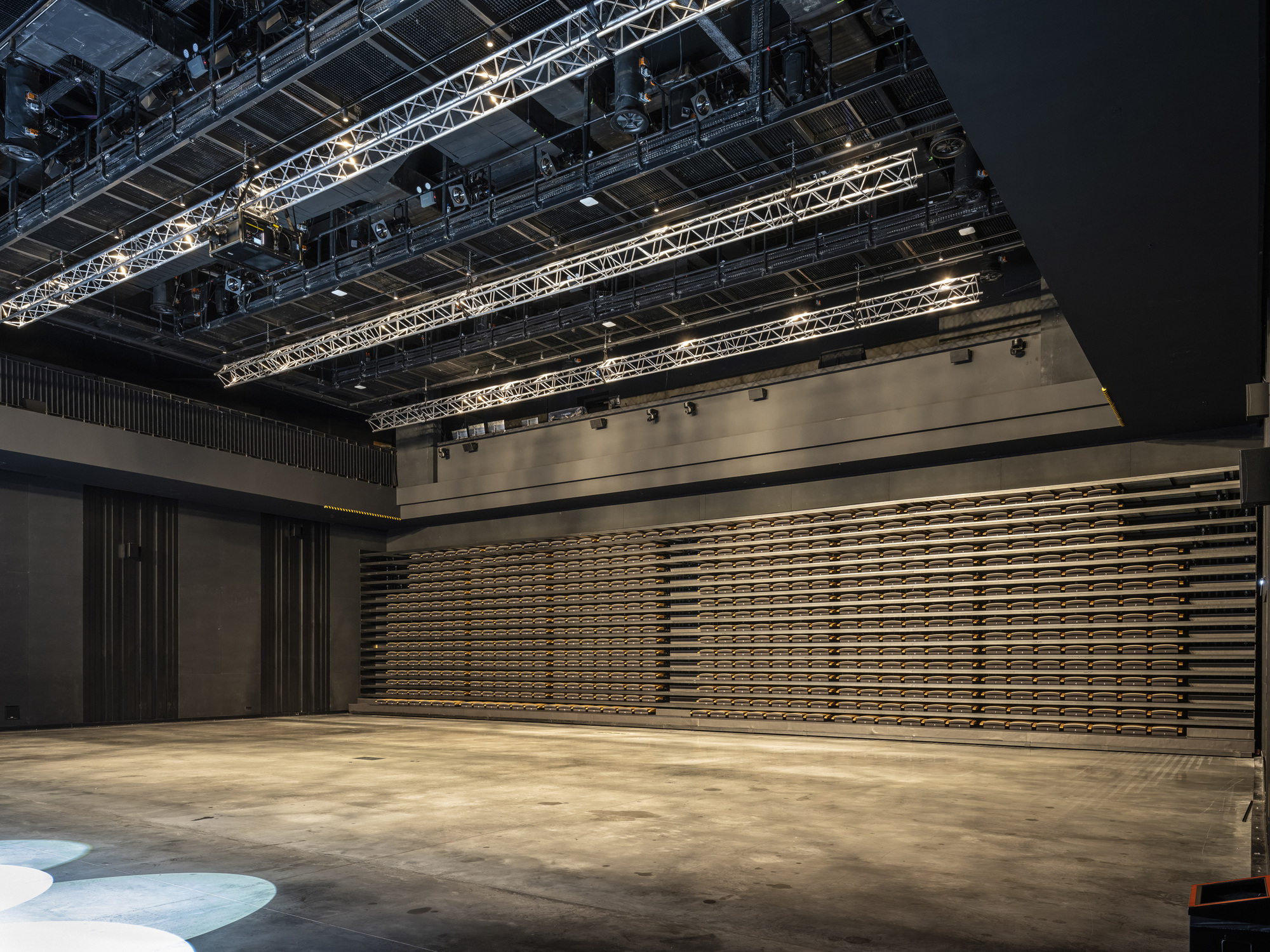 Horizontal wooden slat wall system in partially closed position beneath theatrical lighting grid
