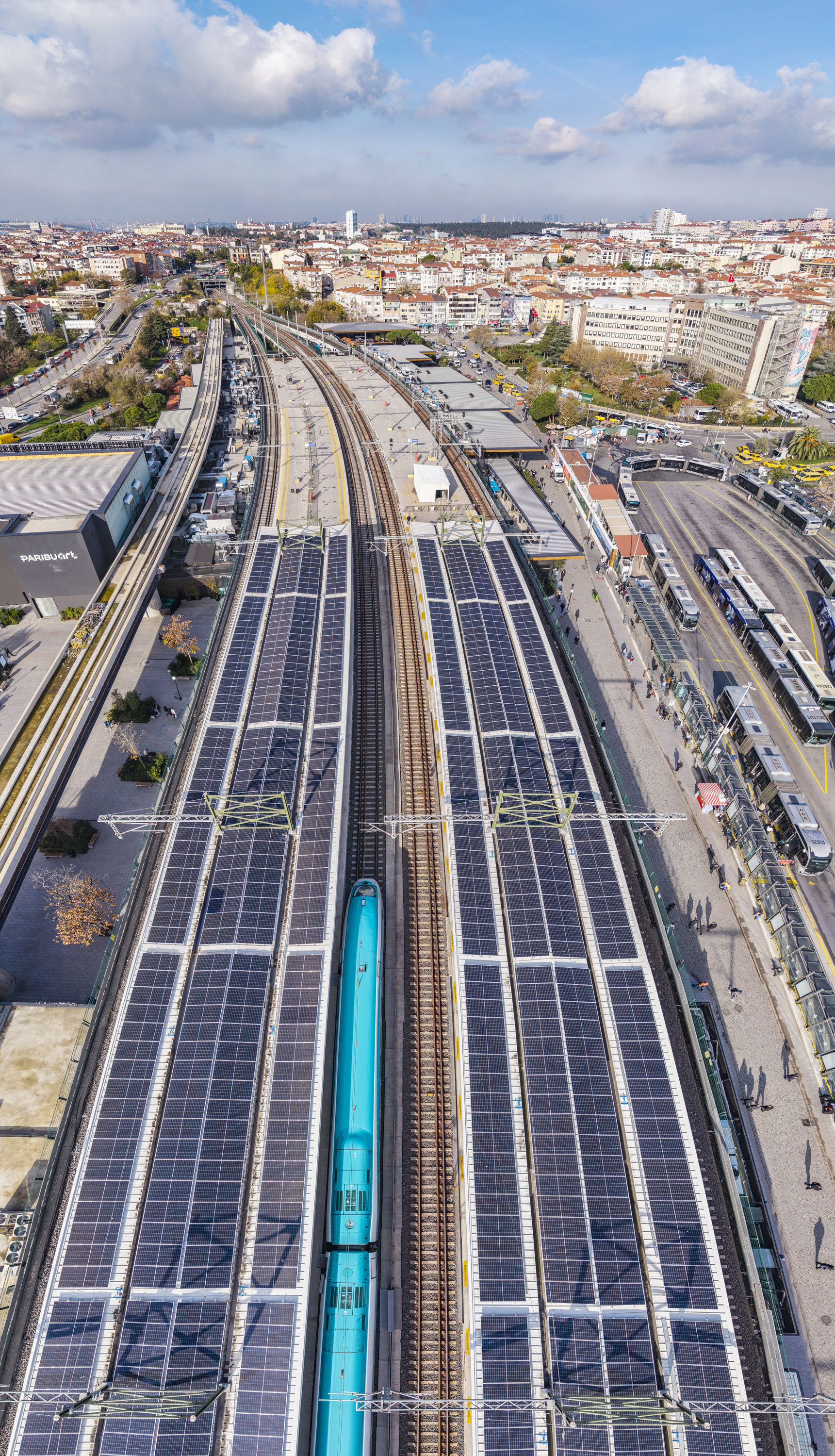 Drone view of platform canopies covered with photovoltaic panels spanning railway tracks below