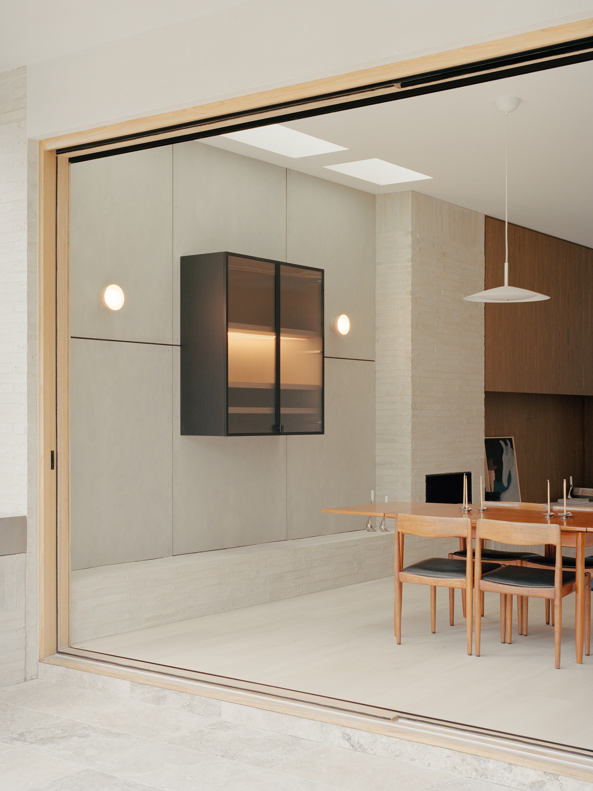 Dining room with timber table viewed through sliding glass doors and overhead skylights