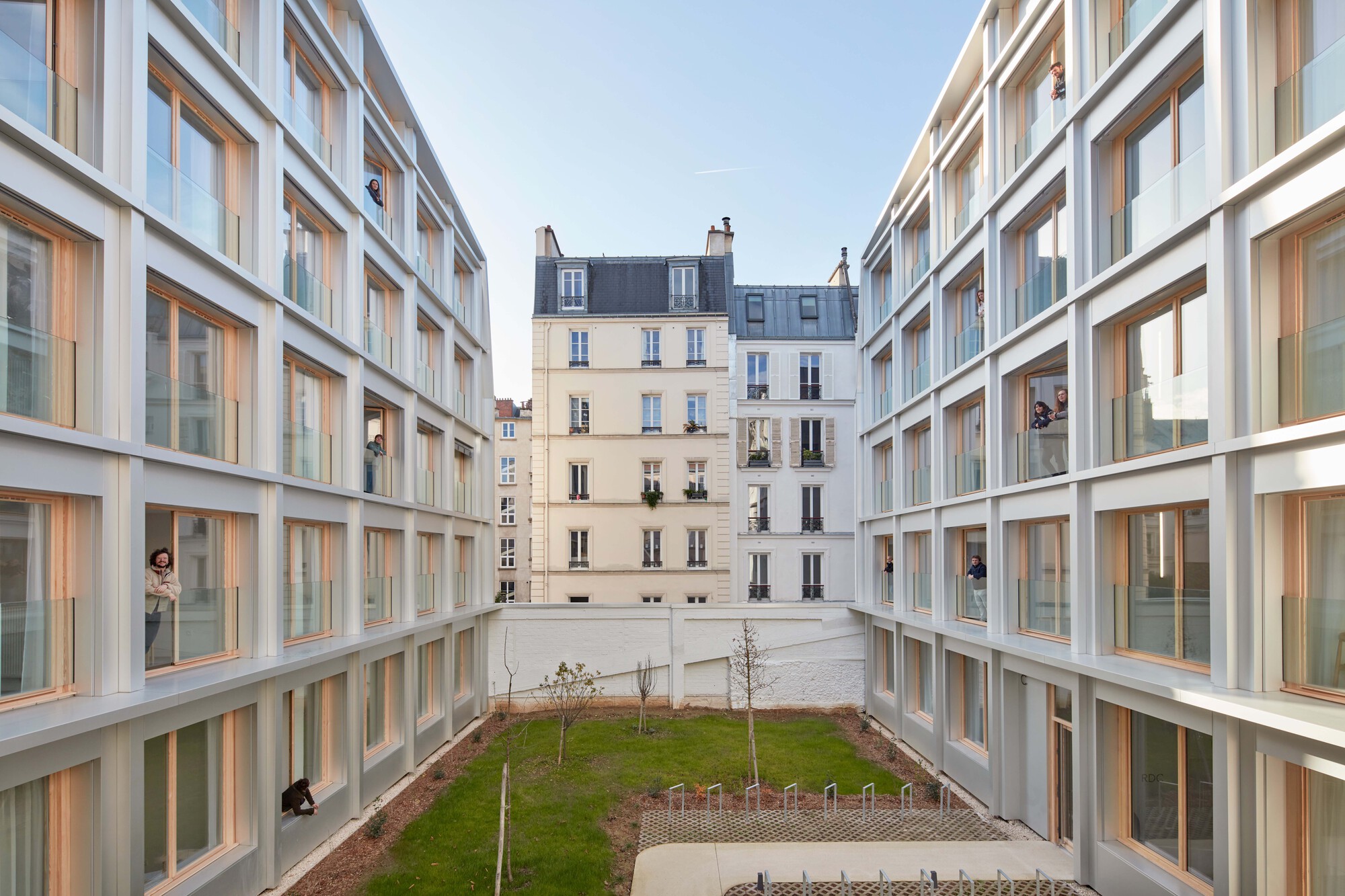 Interior courtyard framed by two new wings with historic apartment building visible beyond the lawn