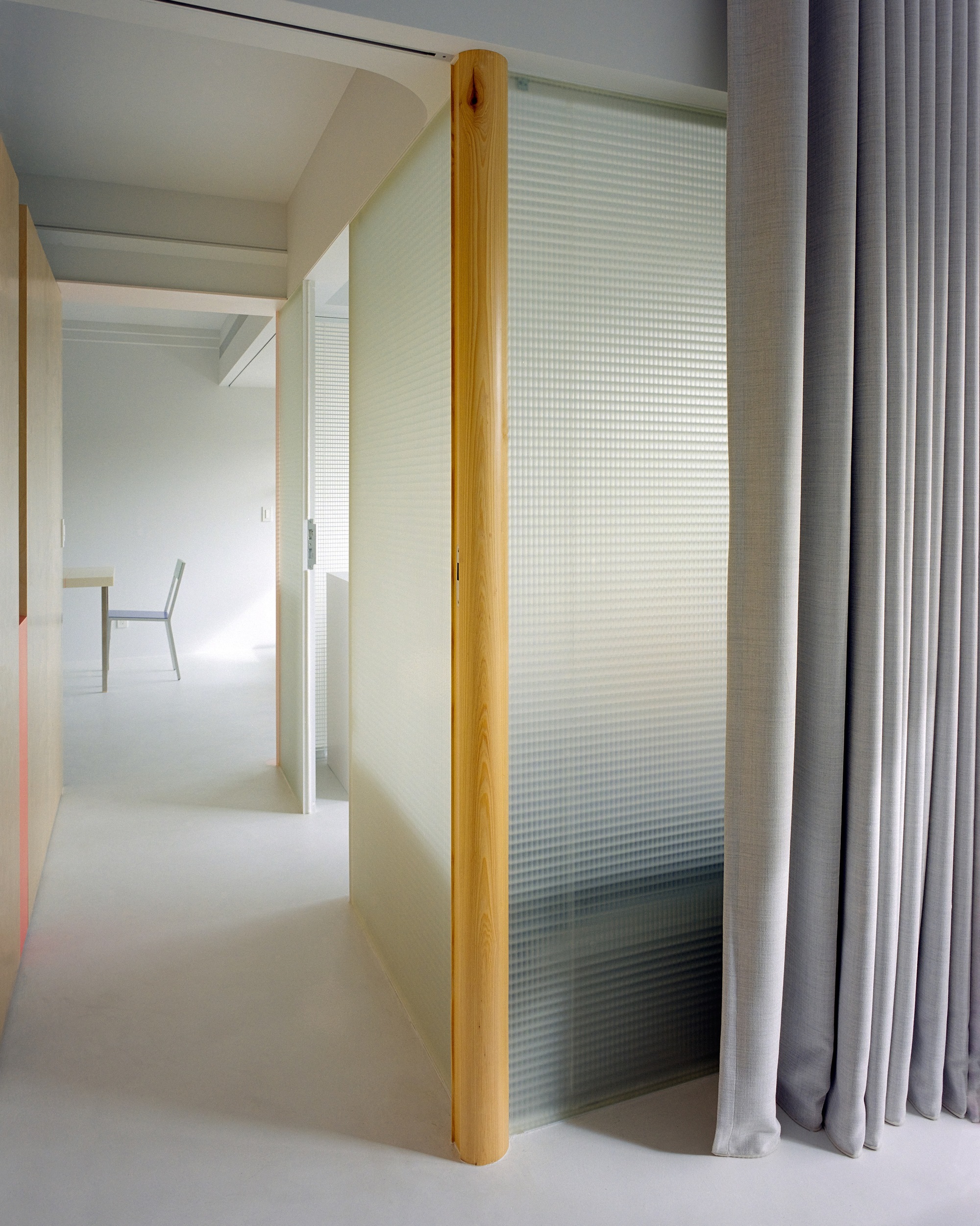 Sliding translucent panel with vertical timber edge and grey curtain drawn to one side
