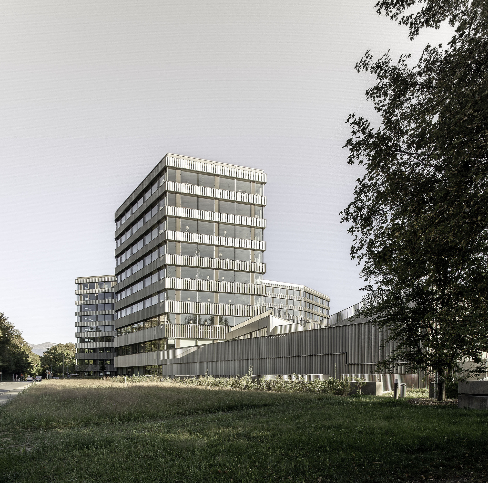 Multi-storey tower with louvered facade rising above a horizontal ribbed base in afternoon light