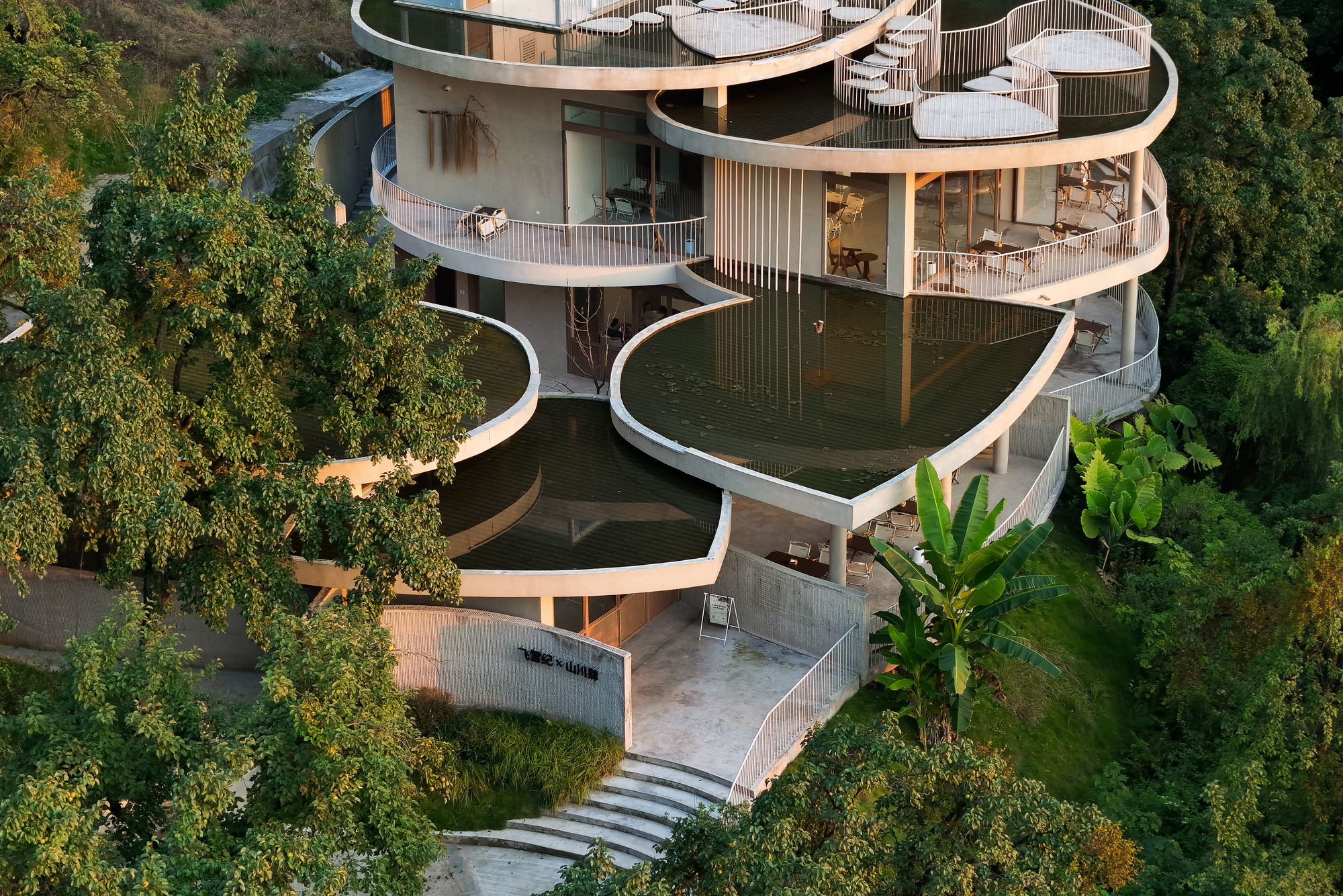 Close view of the undulating balconies with vertical railings and concrete terrace leading to entry steps