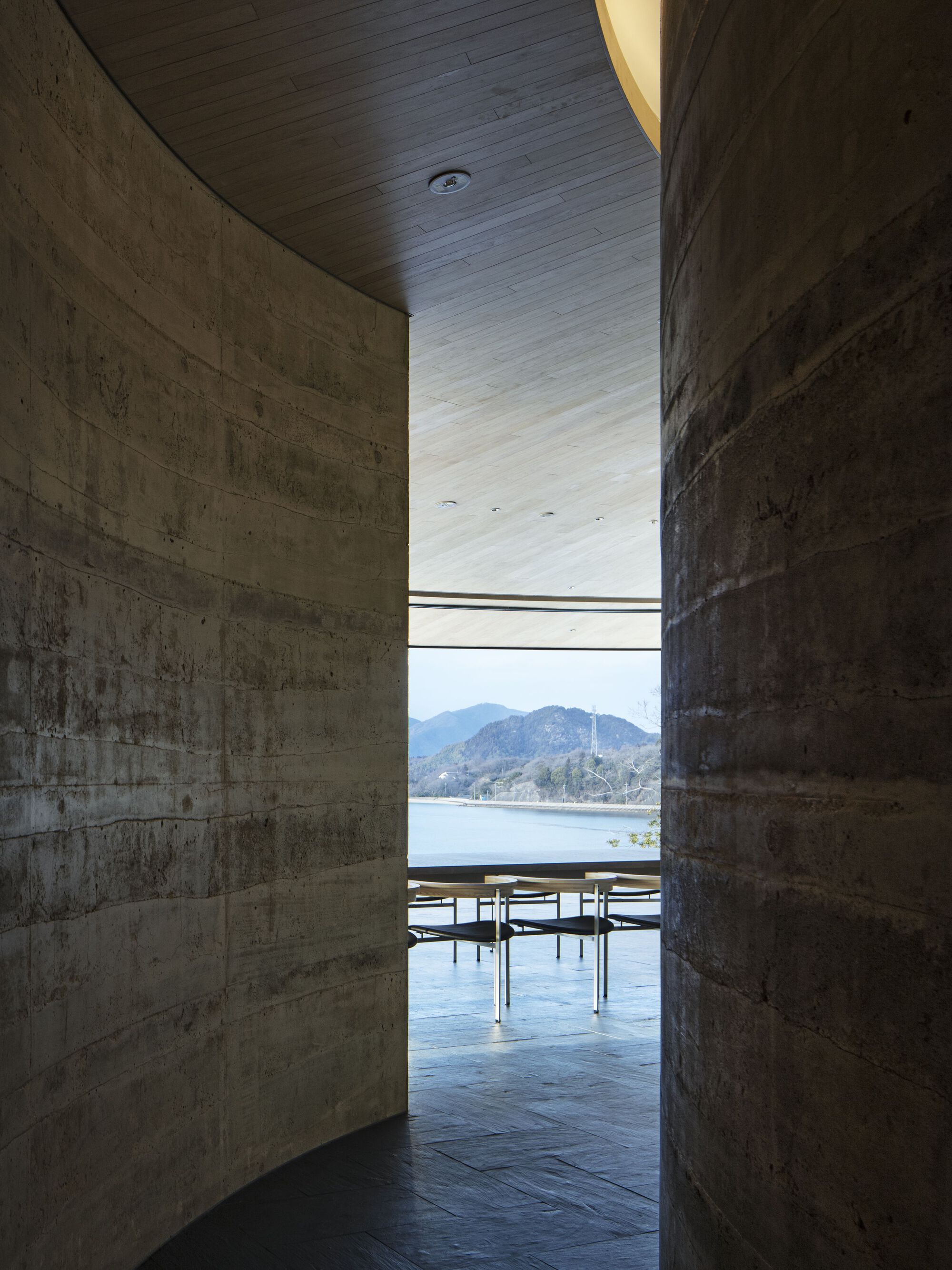 Concrete passageway framing a view of the lake and mountains through a horizontal slot window