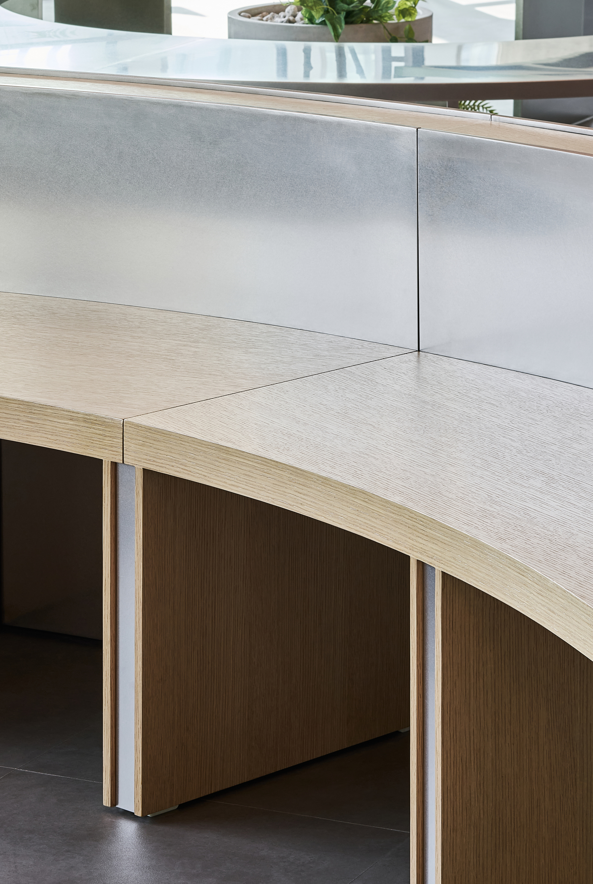 Detail of curved plywood desk edge with metal screen panel and exposed laminated construction