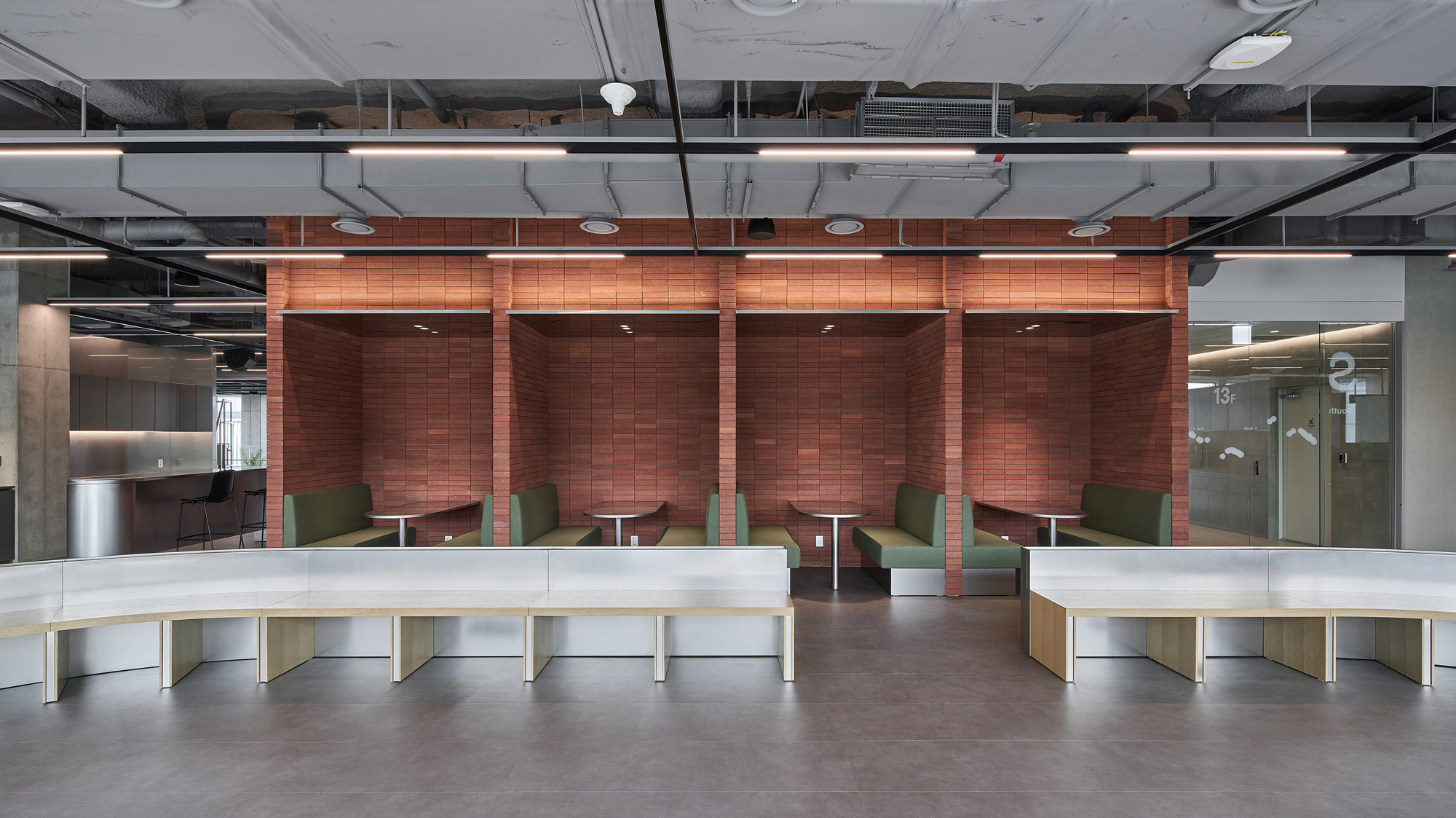 Booth seating area with copper tile alcoves and curved white counters under exposed ductwork