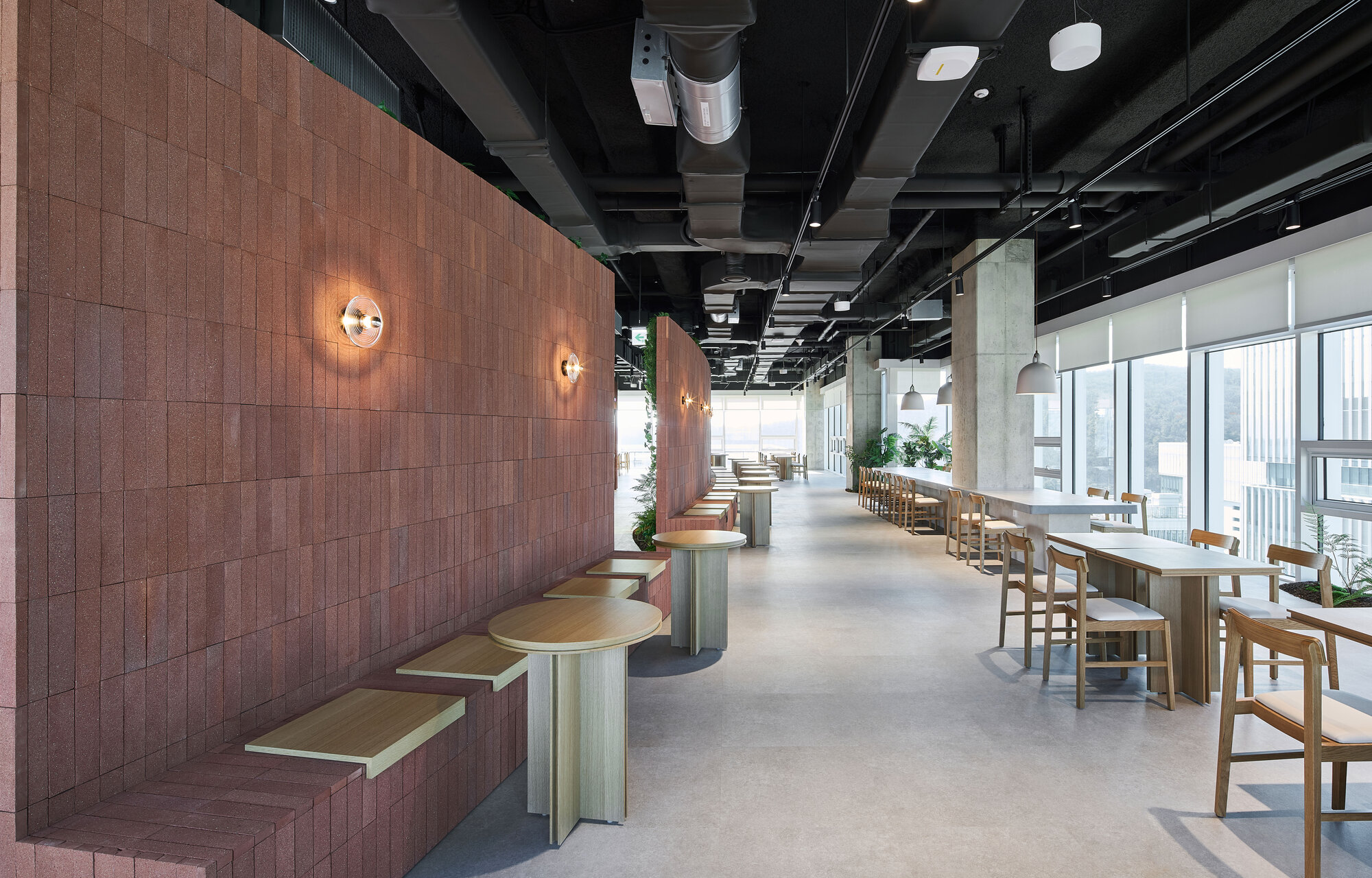 Dining area with copper tile wall, wall sconces, and timber tables along window line