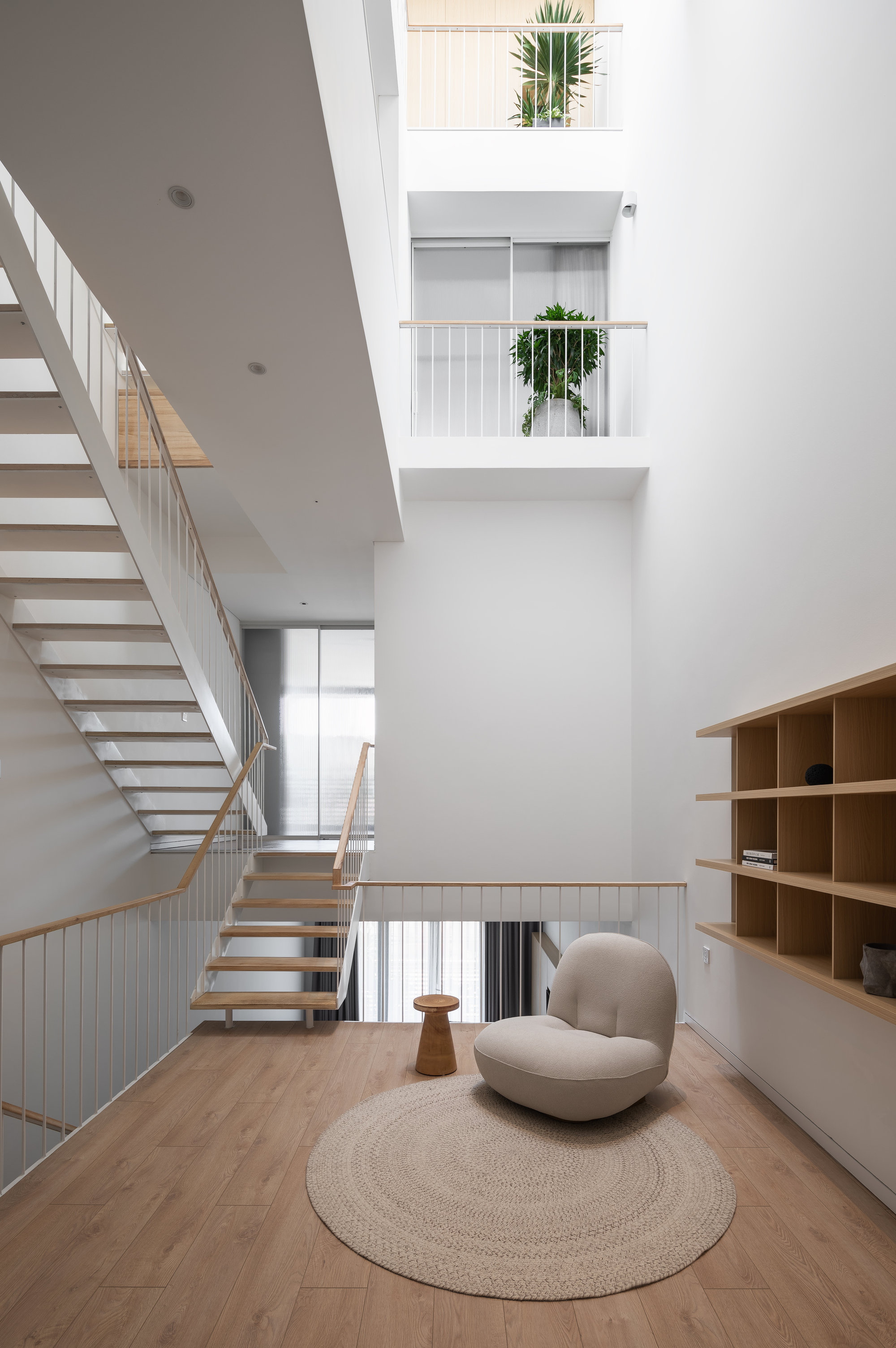 Multi-level interior with open timber stairs, metal railings, and small planted balconies in the void above