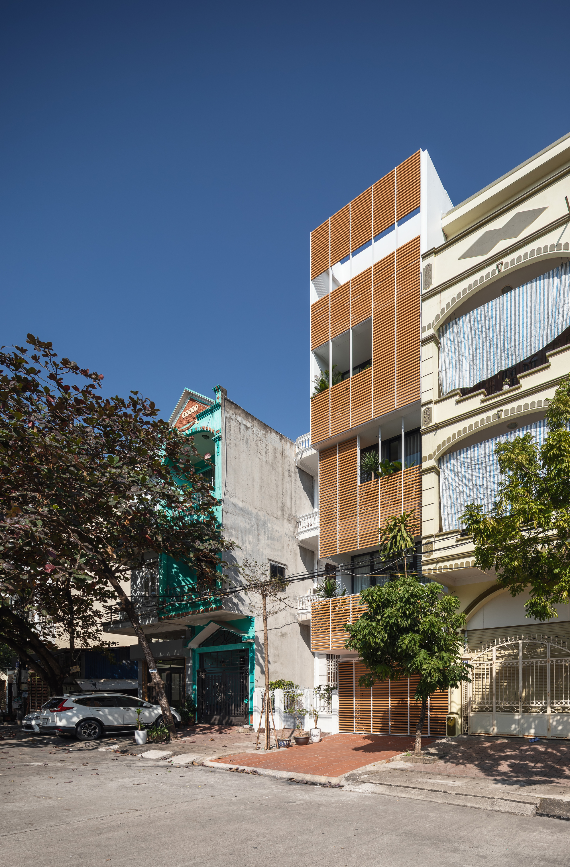 Street view of the narrow wooden louver facade inserted between older residential buildings