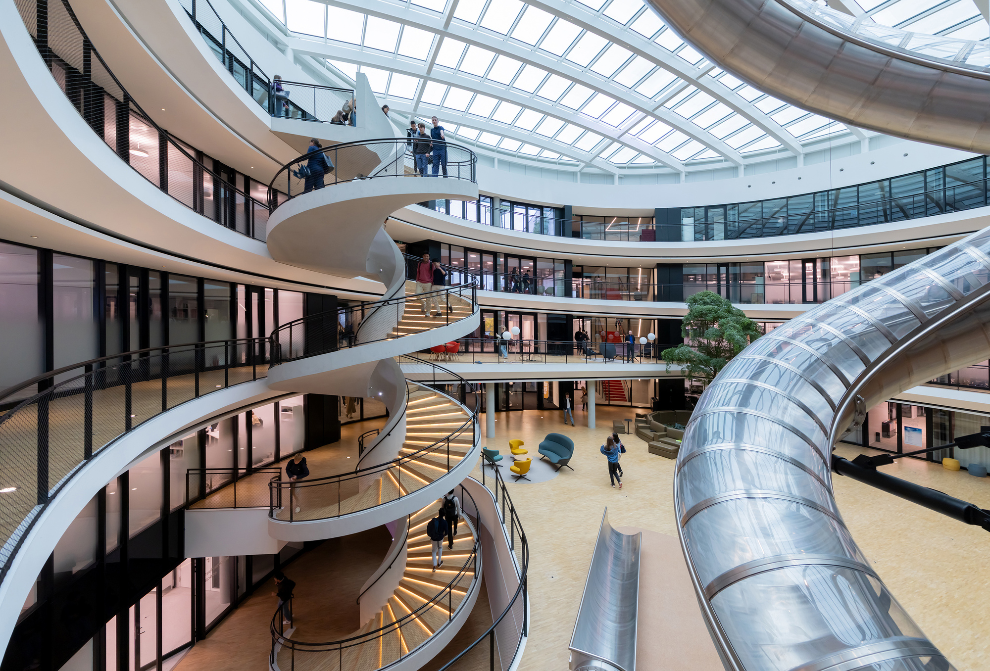 Central atrium with spiraling staircase and tubular slide beneath a glazed skylight