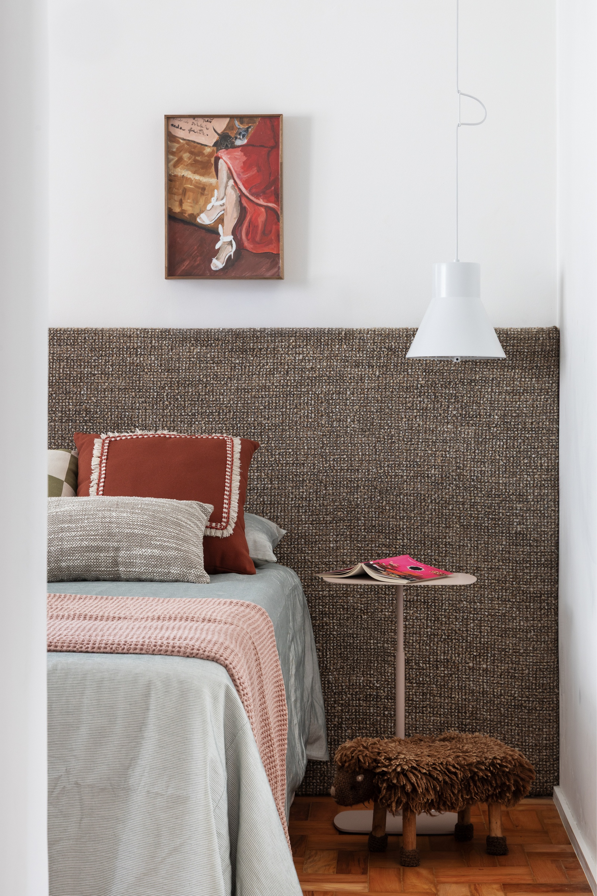 Bedroom with woven textile headboard panel and painting above the bed