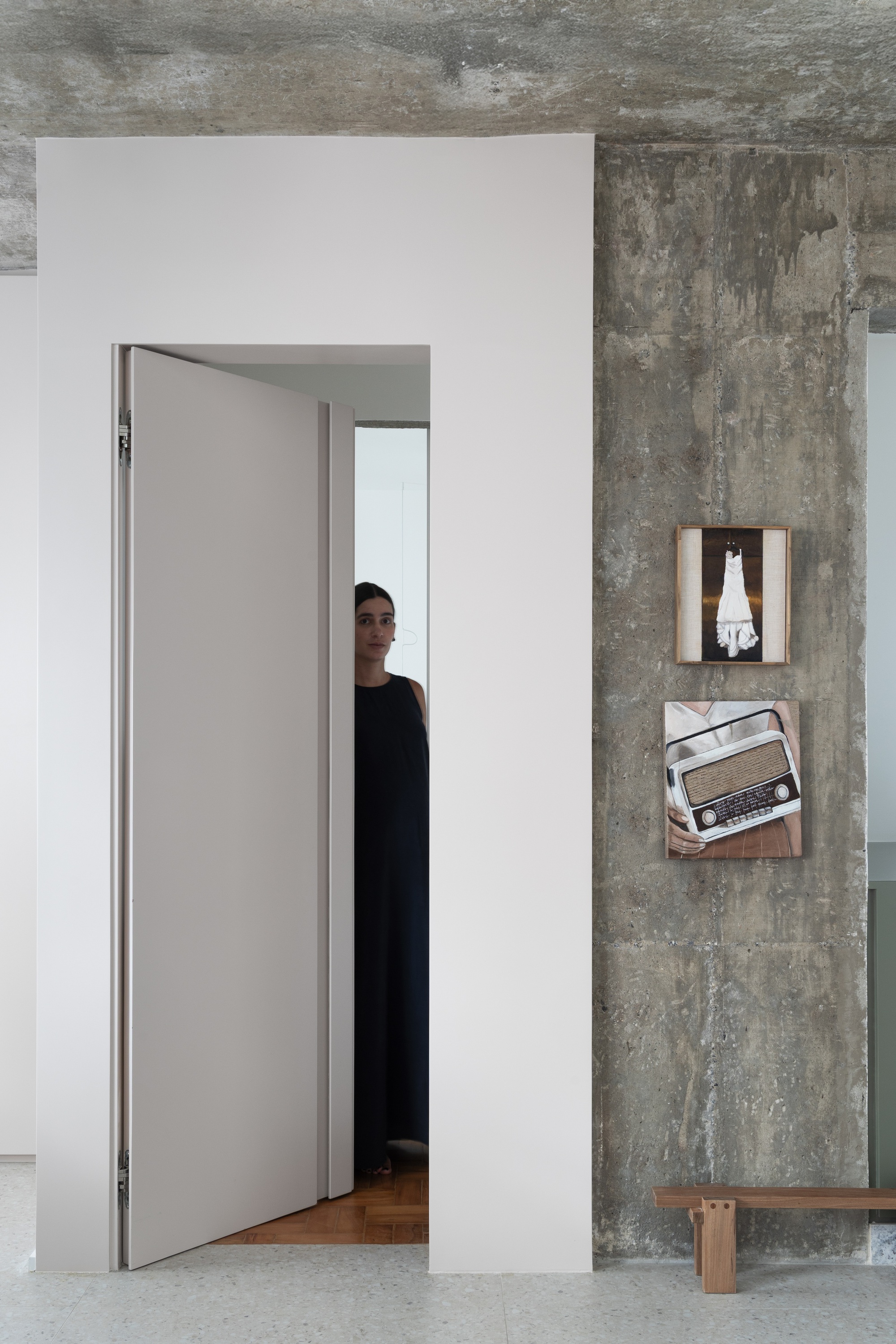 Doorway framed by white walls and exposed concrete ceiling with a person visible beyond