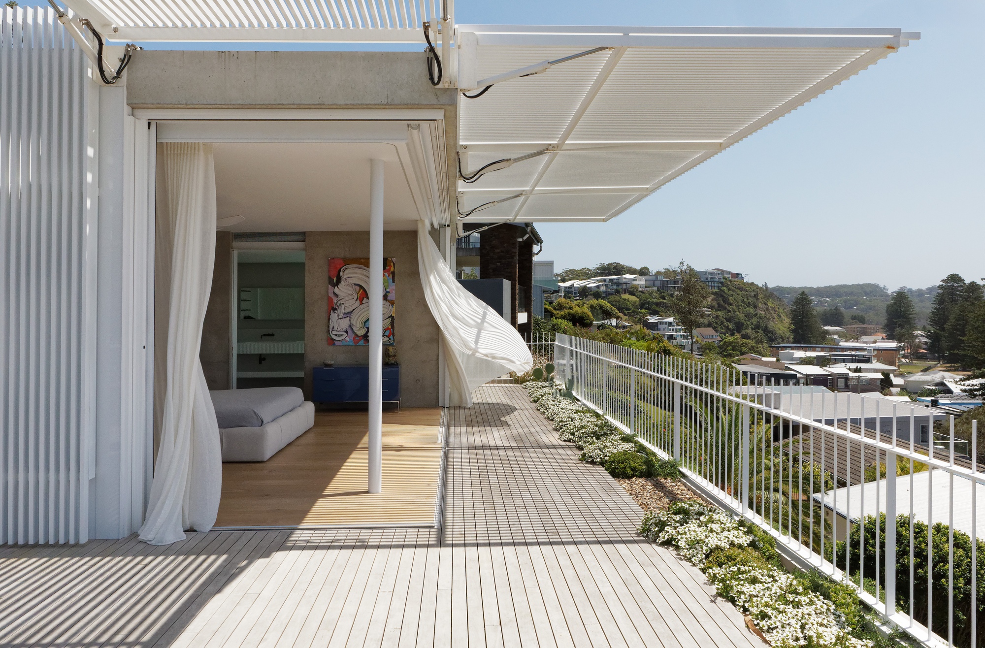 Corner of the timber deck terrace with white fabric canopy billowing in afternoon breeze