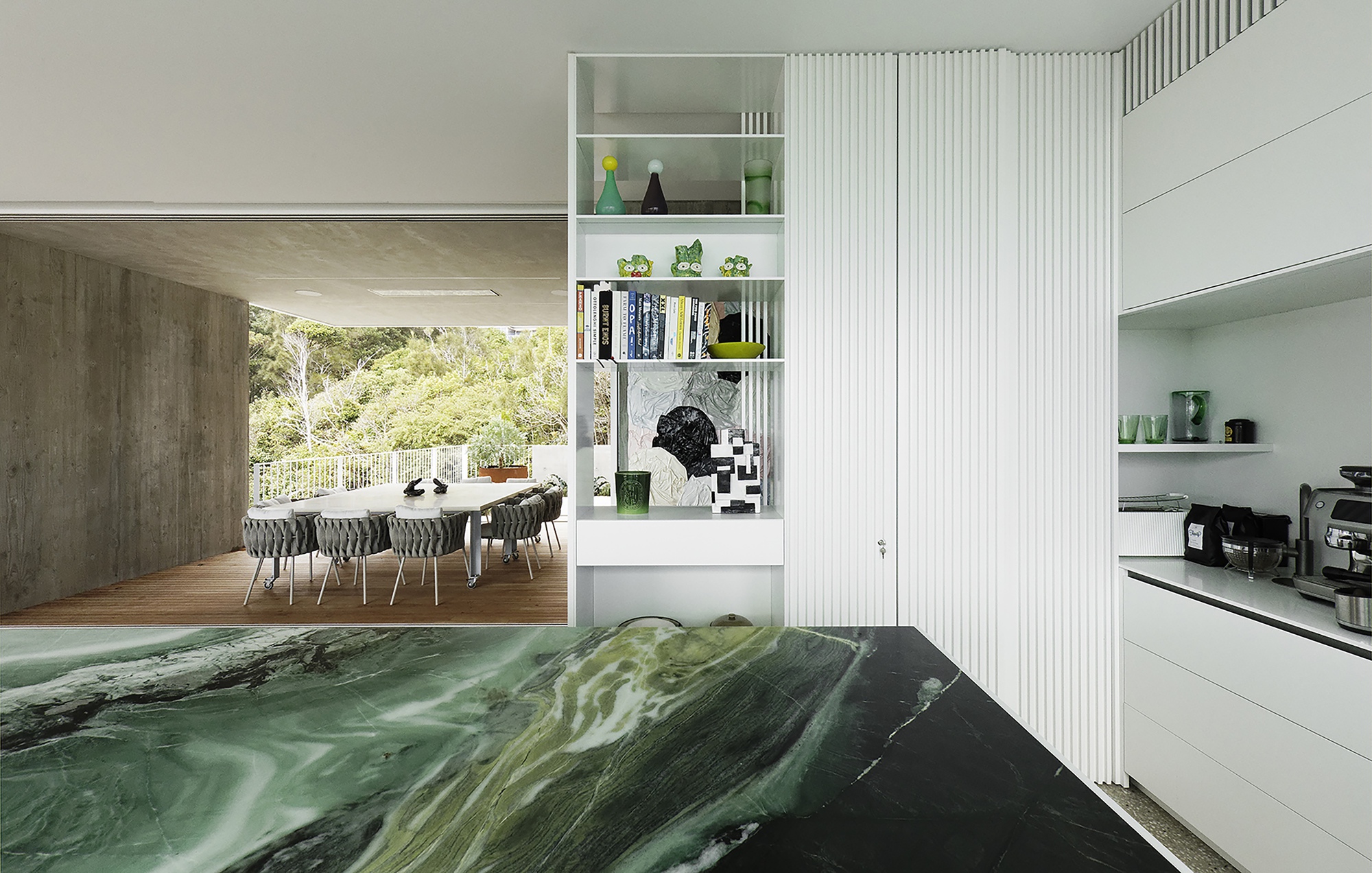 View through the kitchen island toward the dining area with ribbed white partition wall