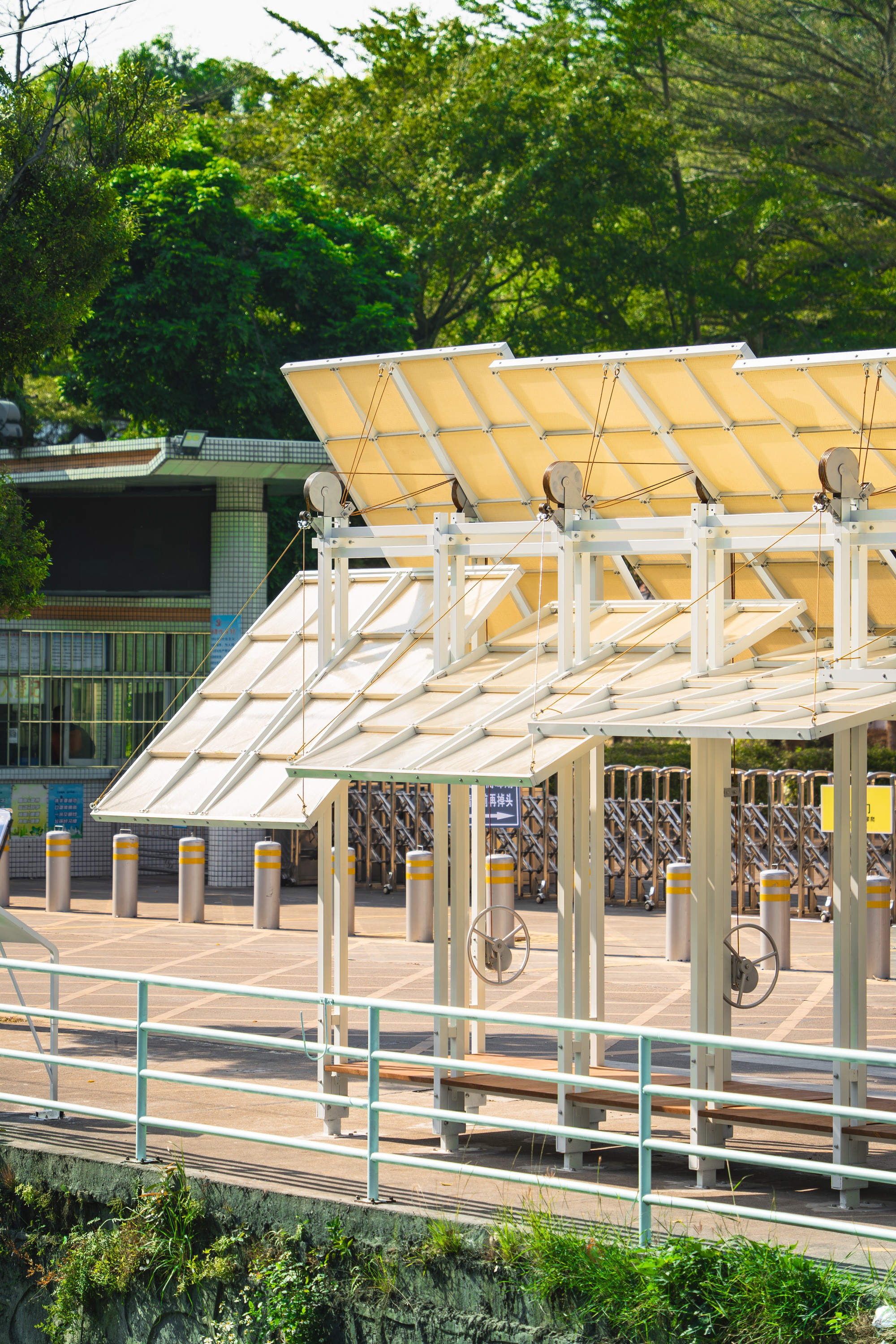 Tilted canopy structure with translucent panels and exposed white steel supports near bike parking