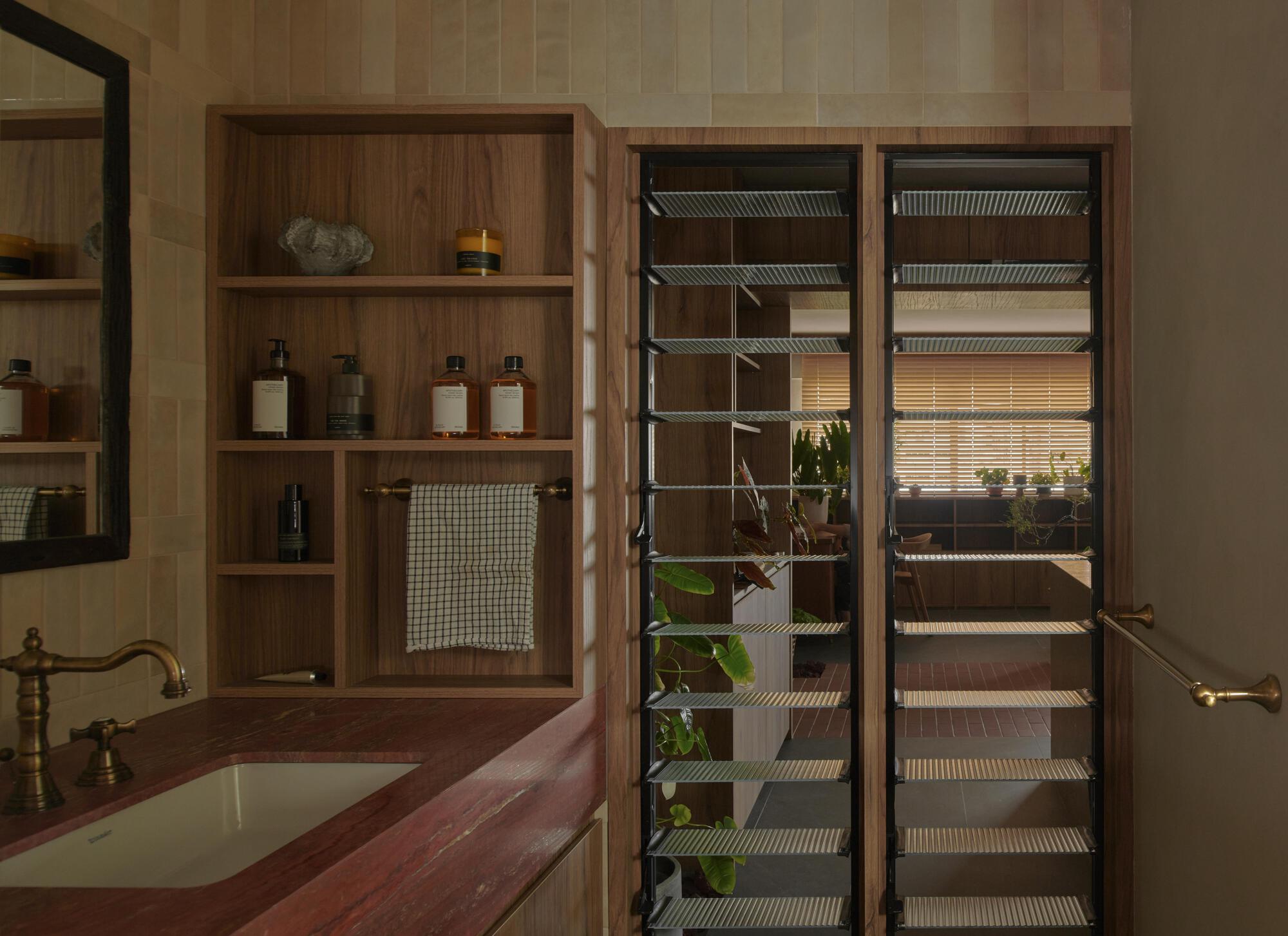 Open shelving unit revealing a glass-doored refrigerator with wire racks and hanging plants