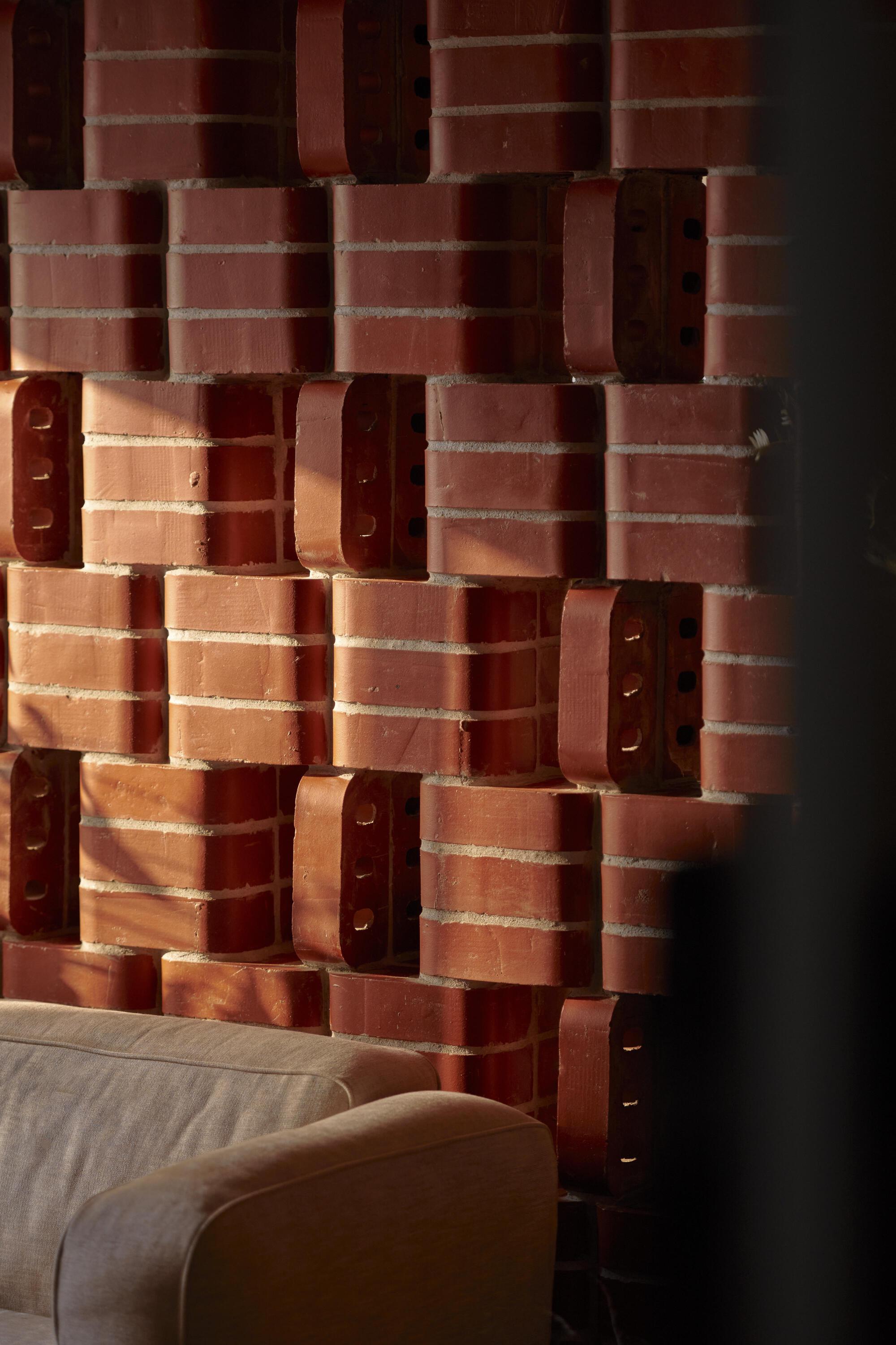 Textured brick wall corner with alternating solid and perforated units in warm afternoon light