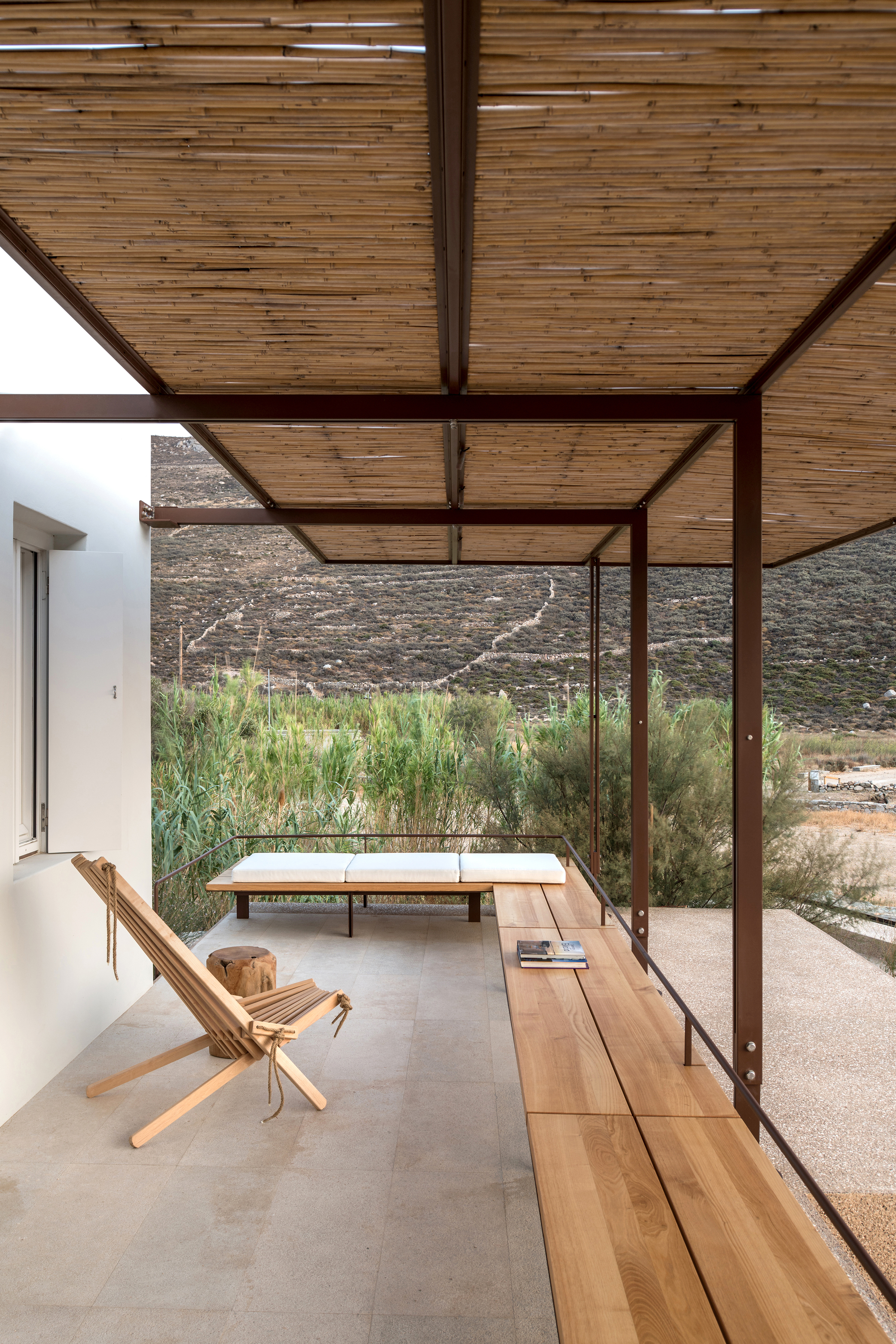 Covered terrace with slatted timber ceiling and steel frame overlooking native grasses and hillside