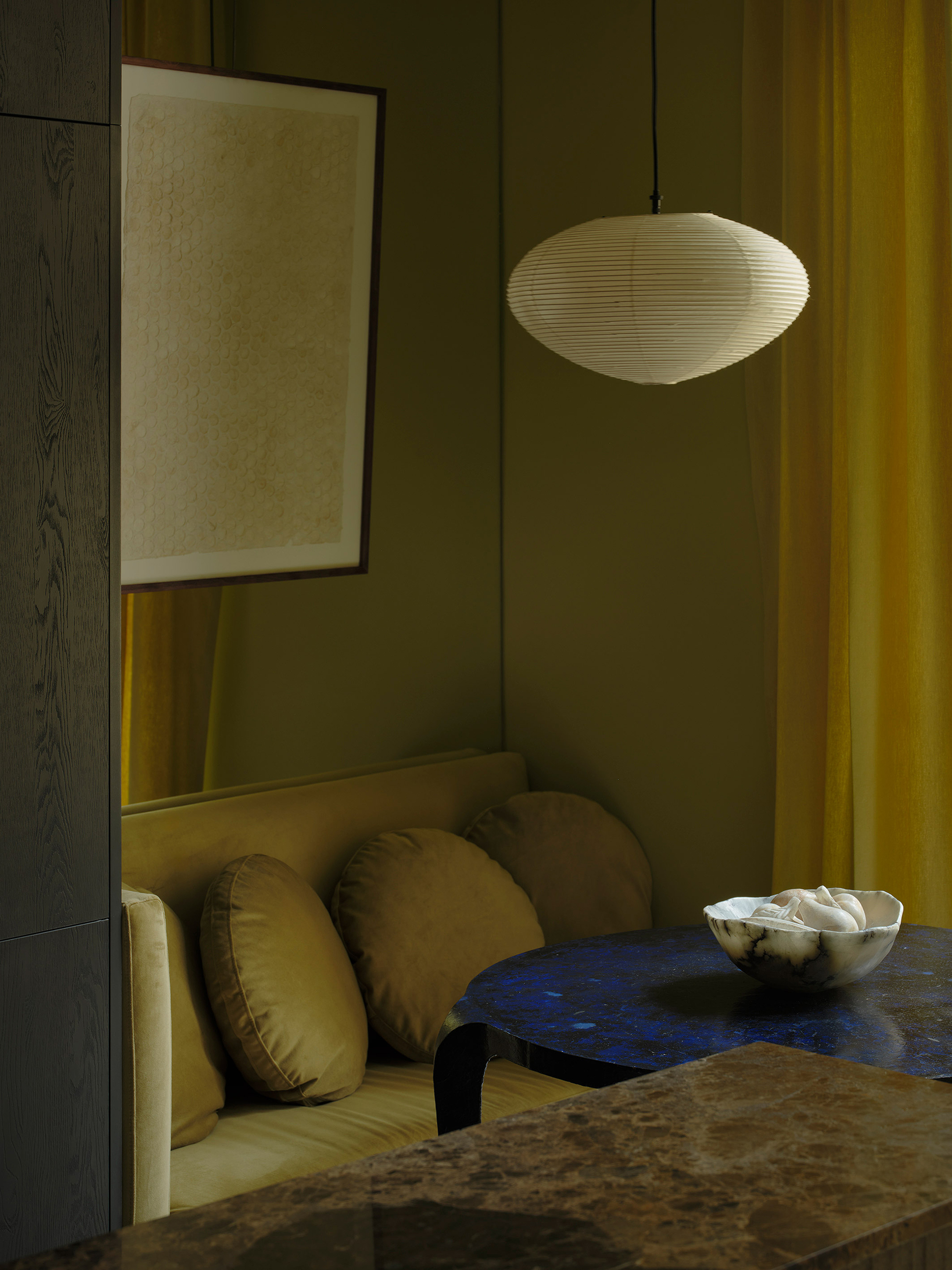 Dining nook with upholstered bench seating, olive paneled walls, and a pendant light fixture