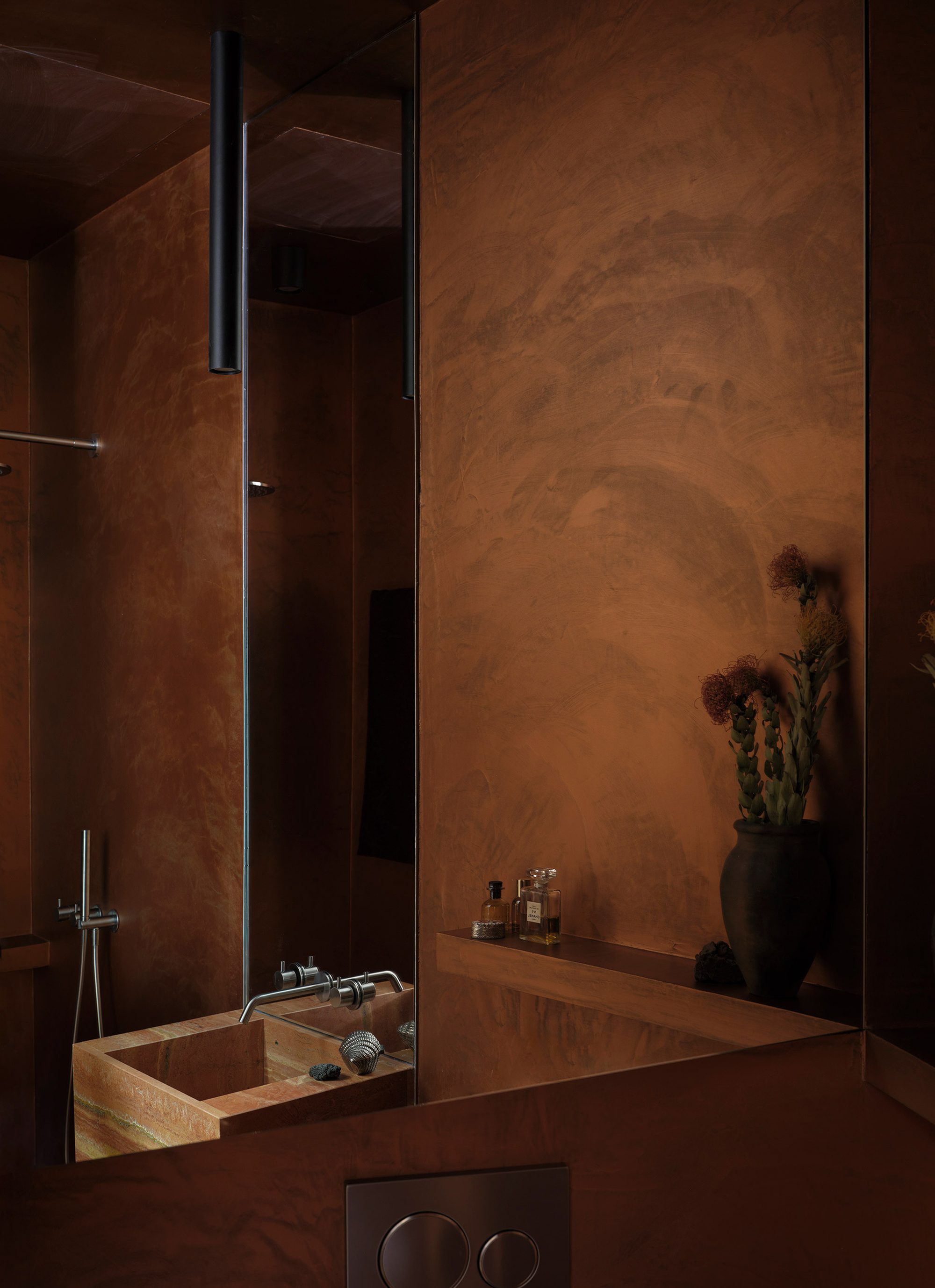 Bathroom sink with copper-toned walls and a wall-mounted mirror reflecting dried flowers