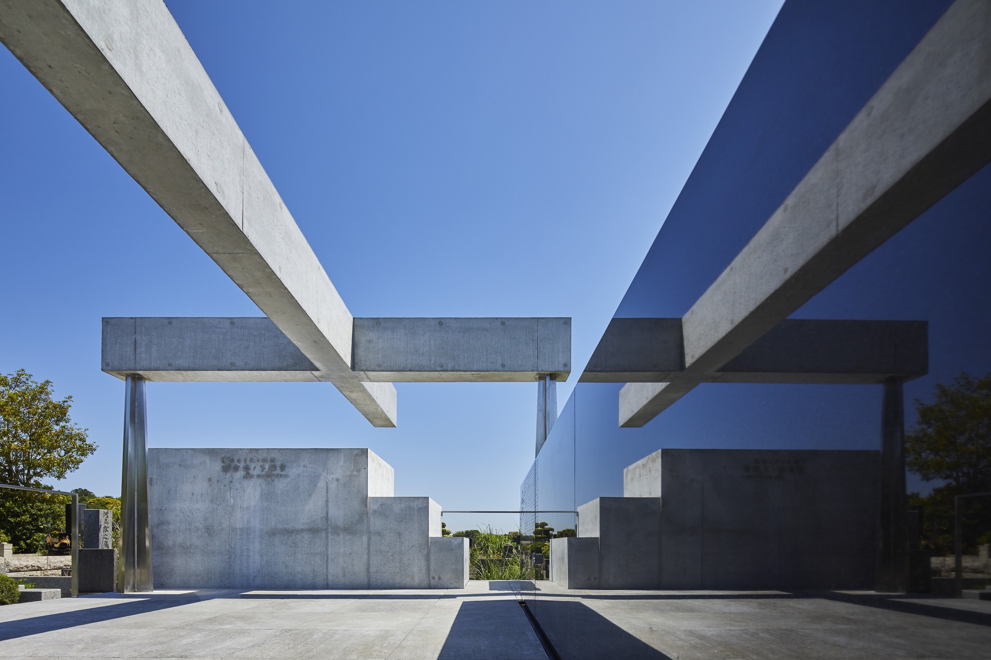 View through the intersecting concrete beam framework showing layered horizontal planes and glass partition in bright sunlight