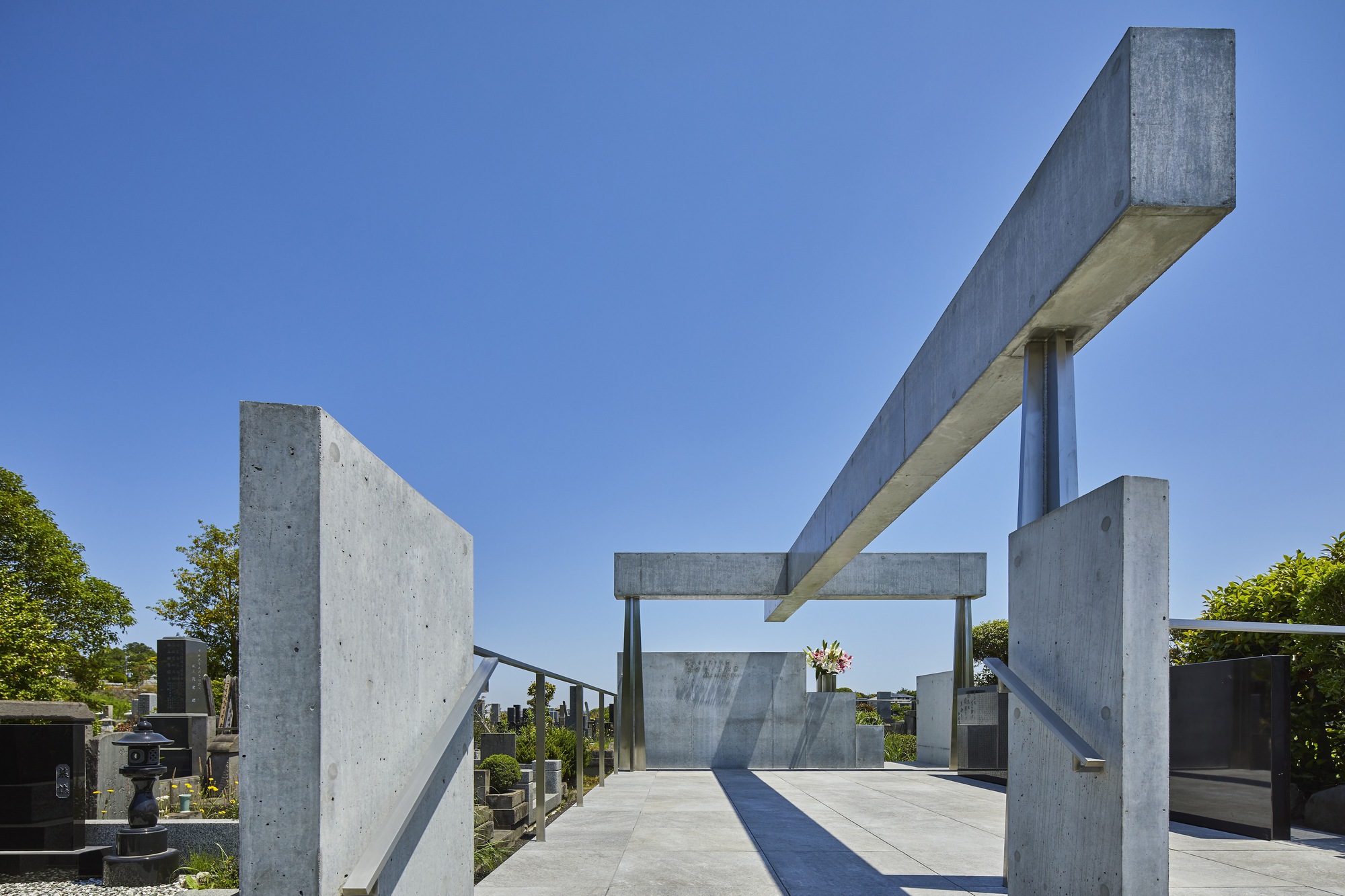 Concrete portal frame structure with columns and beams over a paved plaza under clear blue sky