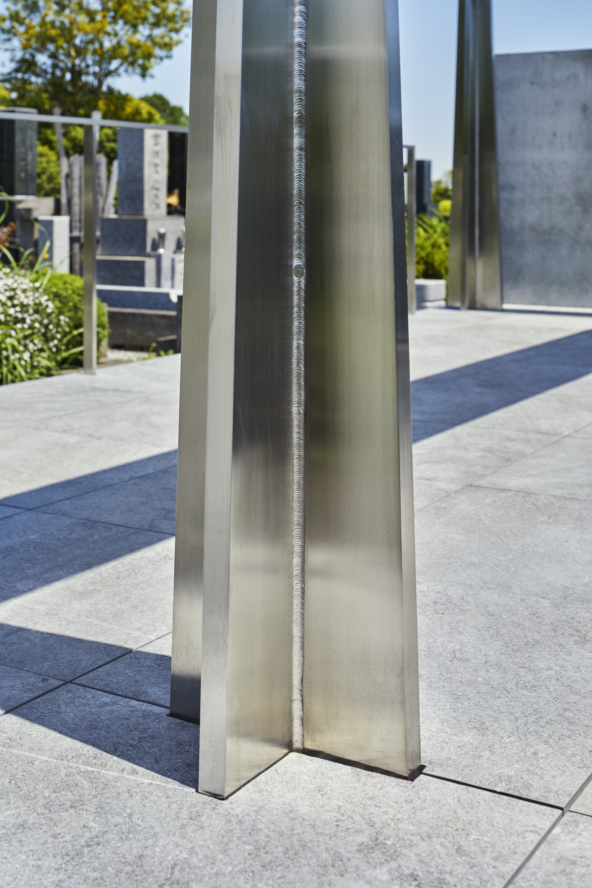 Close-up of a polished stainless steel column with exposed welded seam in bright daylight