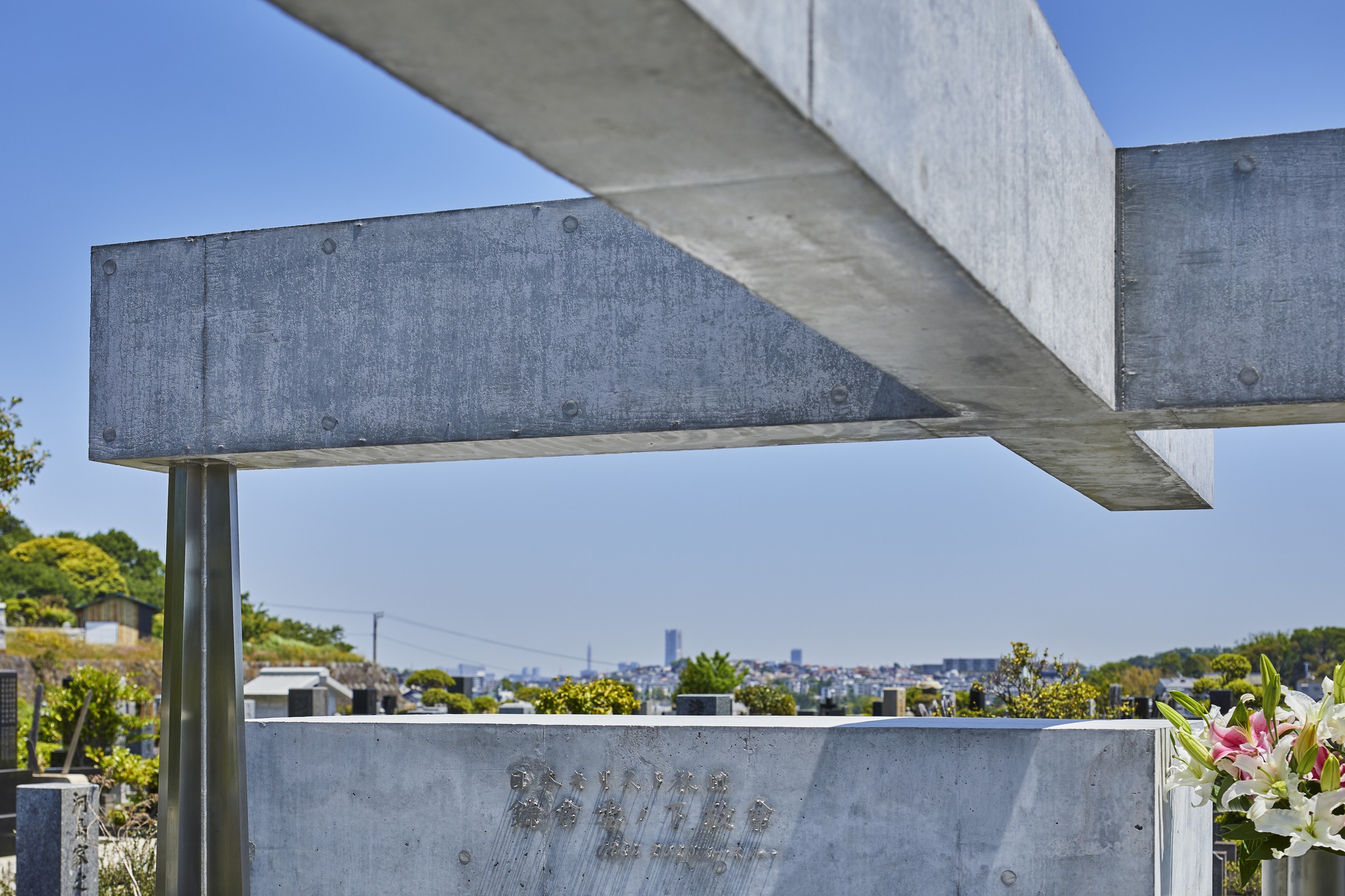 Underside of cantilevered concrete beams with exposed formwork ties above a distant tree line