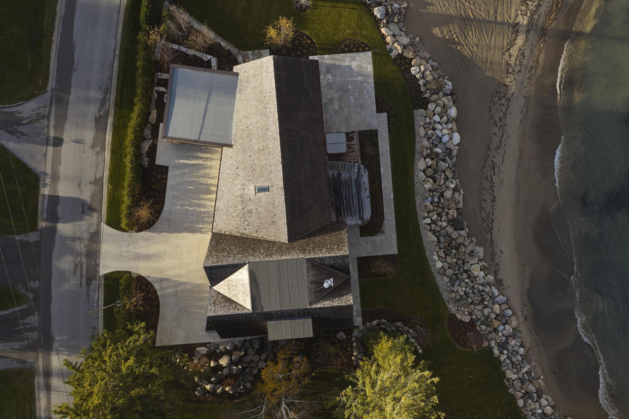 Aerial view of the interlocking volumes with courtyard and planted beds along the rocky shoreline