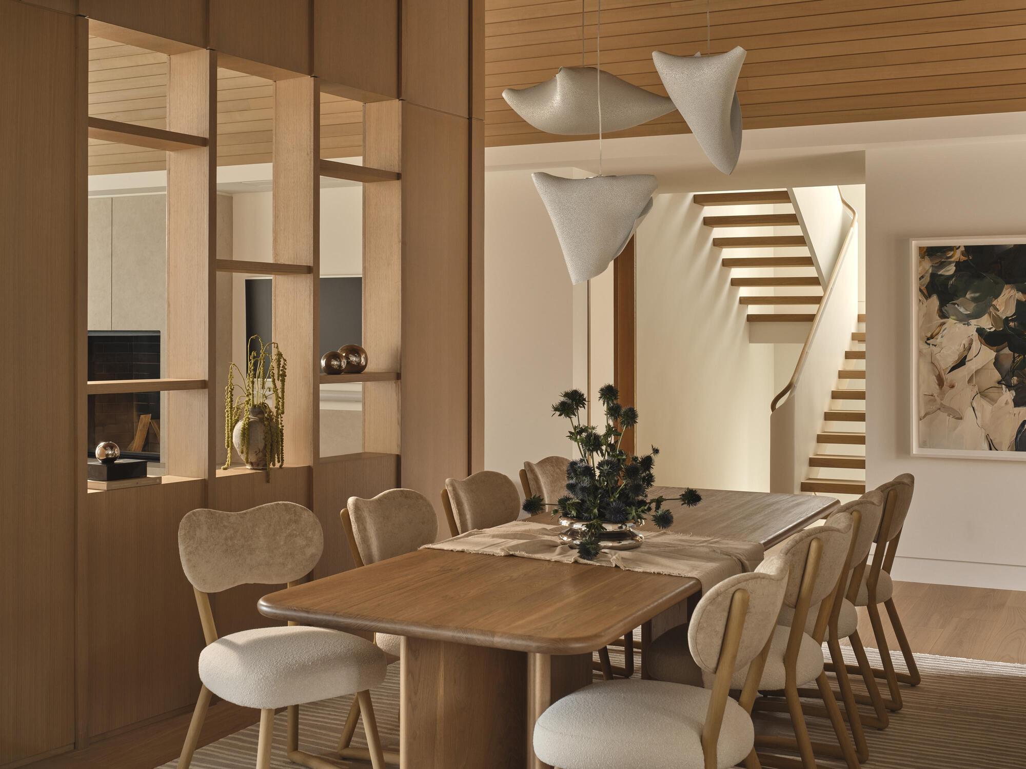 Dining area with open shelving partition and timber staircase visible in the evening light